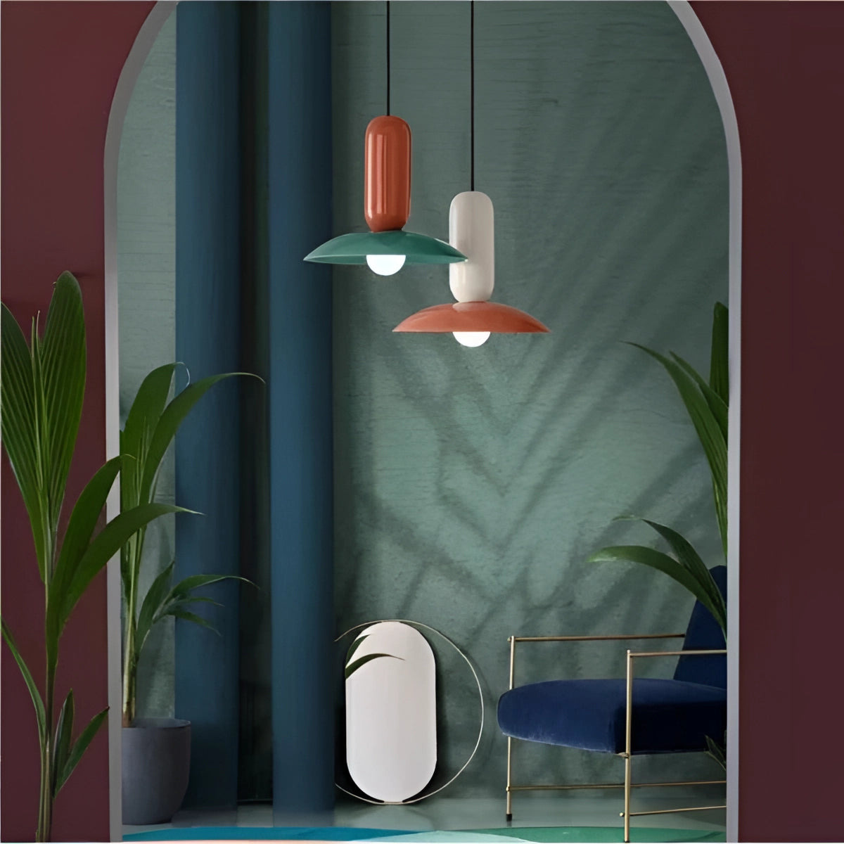 Modern colorful pendant lights hanging above a Scandinavian-style kitchen and dining area, with a houseplant in a flowerpot on a rectangular table, chairs, and a window in the background.