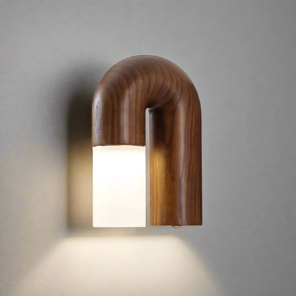 Modern curved wooden wall sconce with a minimalist LED arch design, featuring a natural wood finish and mounted on a rectangular wooden base.