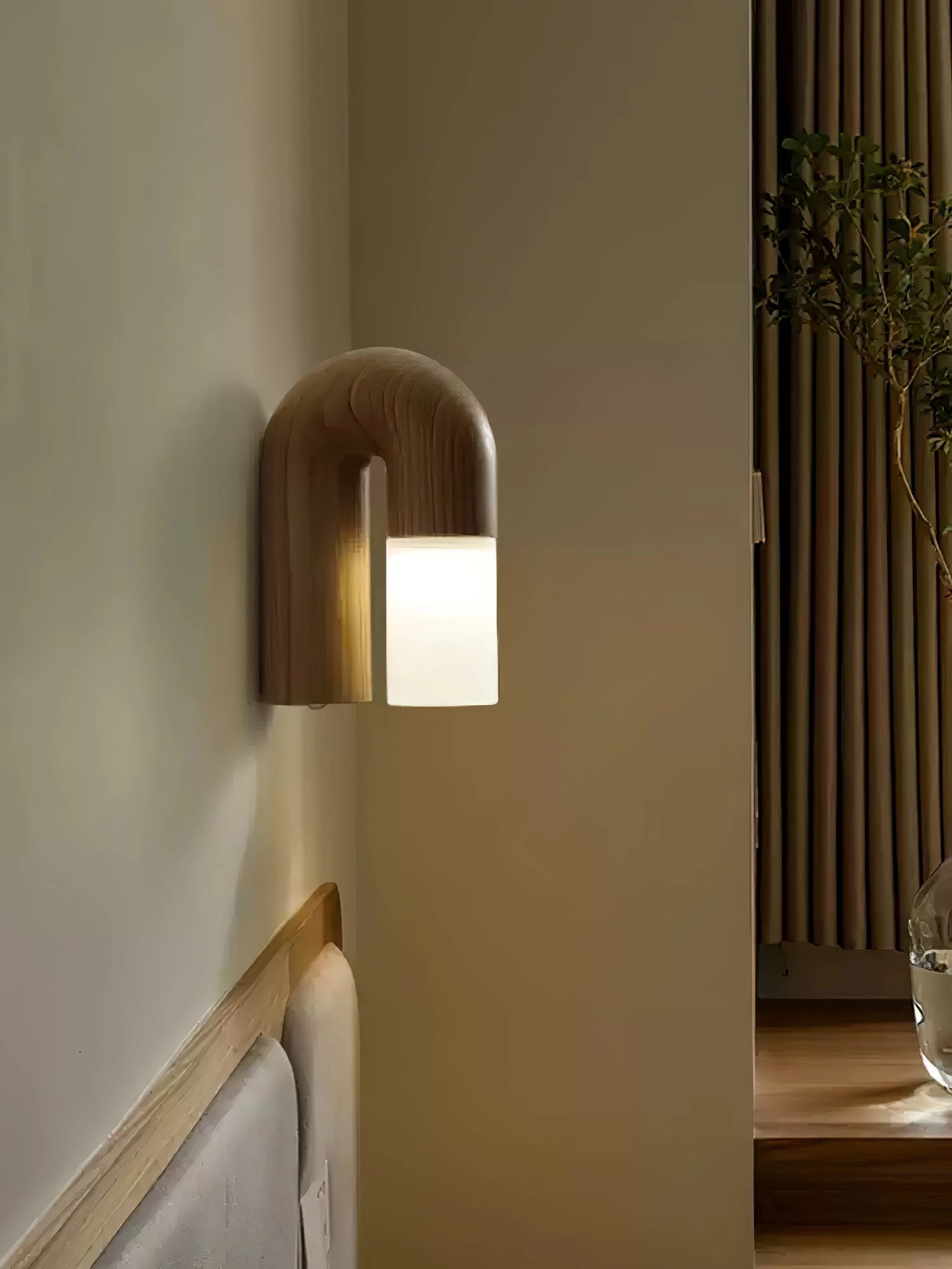 Modern curved wooden wall sconce with a minimalist arch design featuring LED lighting, mounted on a hardwood wall.