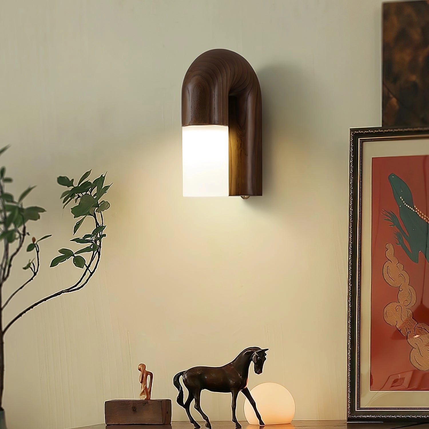 Modern curved wooden wall sconce with LED light fixture mounted on a wall, surrounded by a stylish interior featuring a houseplant, art, and a window.