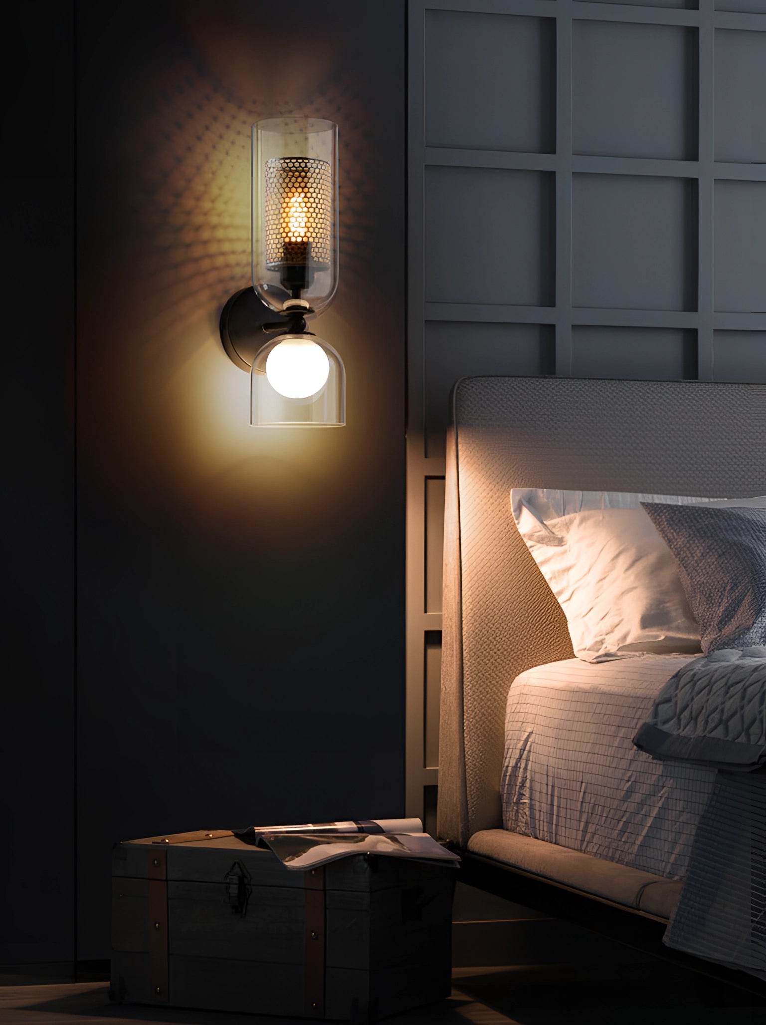 Modern cylindrical glass wall sconce featuring a bronze mesh shade, mounted on a wall, illuminating a stylish interior space.