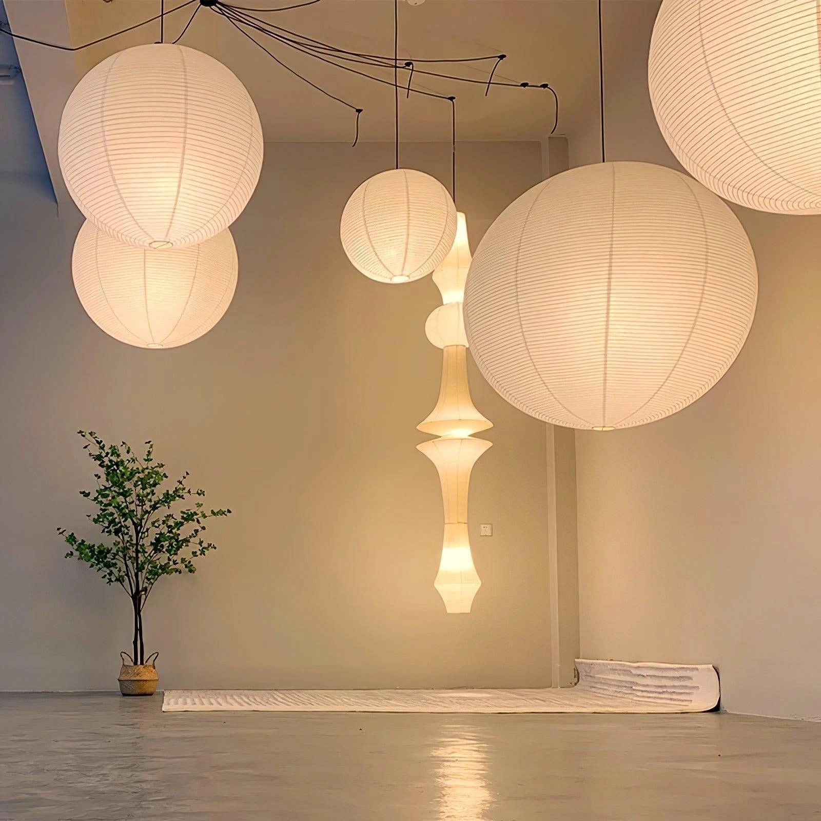 Modern designer white paper lantern pendant providing minimalist ambient lighting, hanging in an interior space, showcasing its artistic design and material properties.