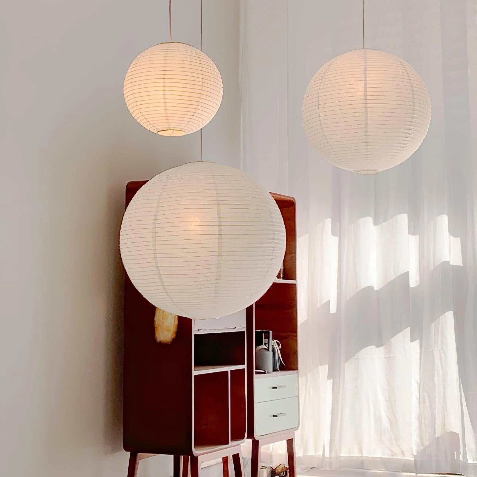 Modern designer paper lantern pendant light with a minimalist design, featuring a soft-textured shade that creates ambient lighting, showcased in an interior setting.
