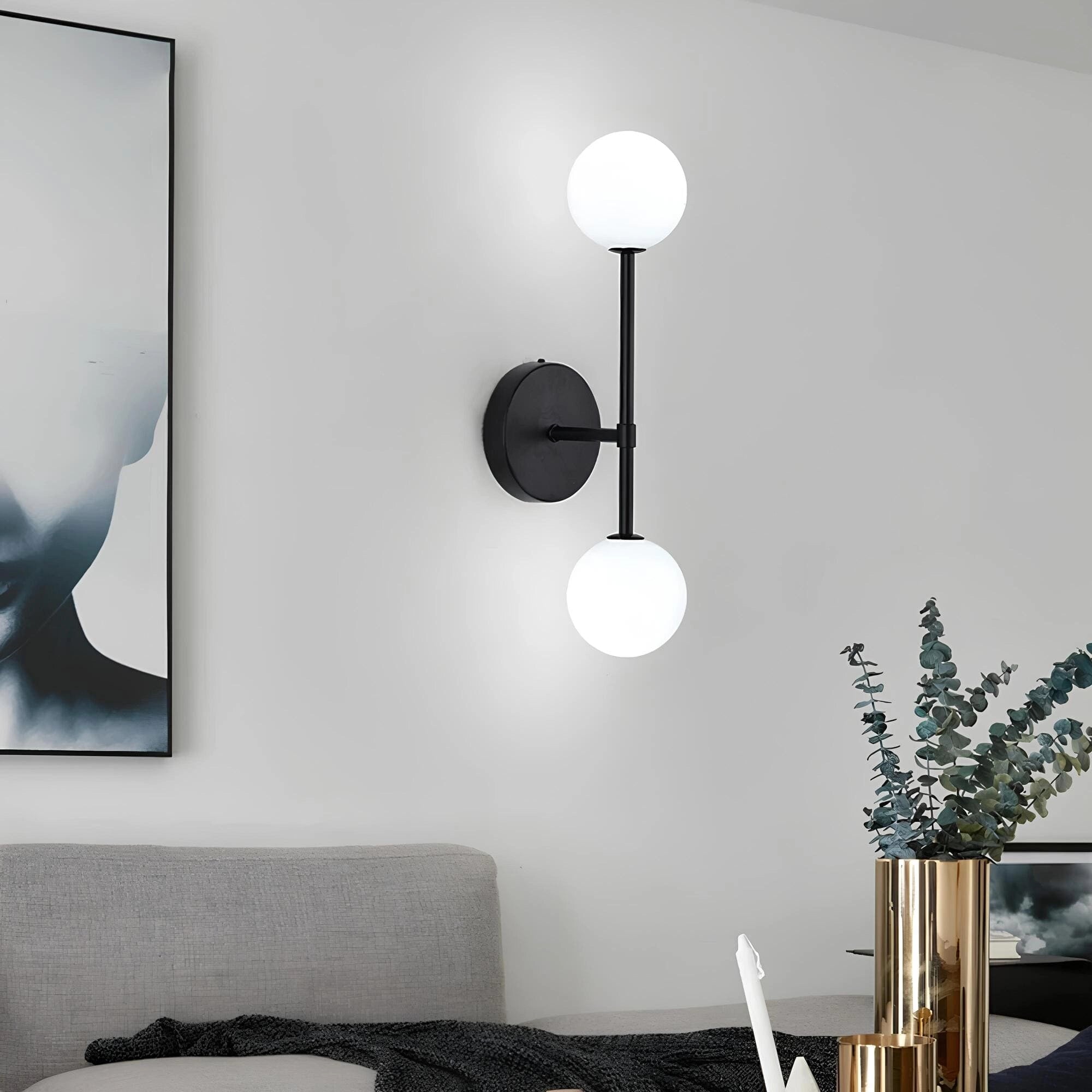 Modern double globe wall sconce with a minimalist design, featuring two round LED lights mounted on a sleek, rectangular black and white fixture against a neutral-colored interior wall.