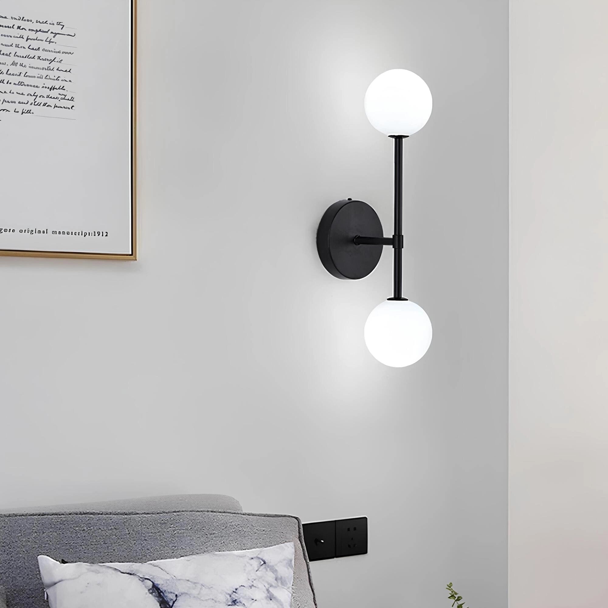 Modern black double globe wall sconce mounted on a white wall, showcasing minimalist LED design suitable for bedroom lighting.