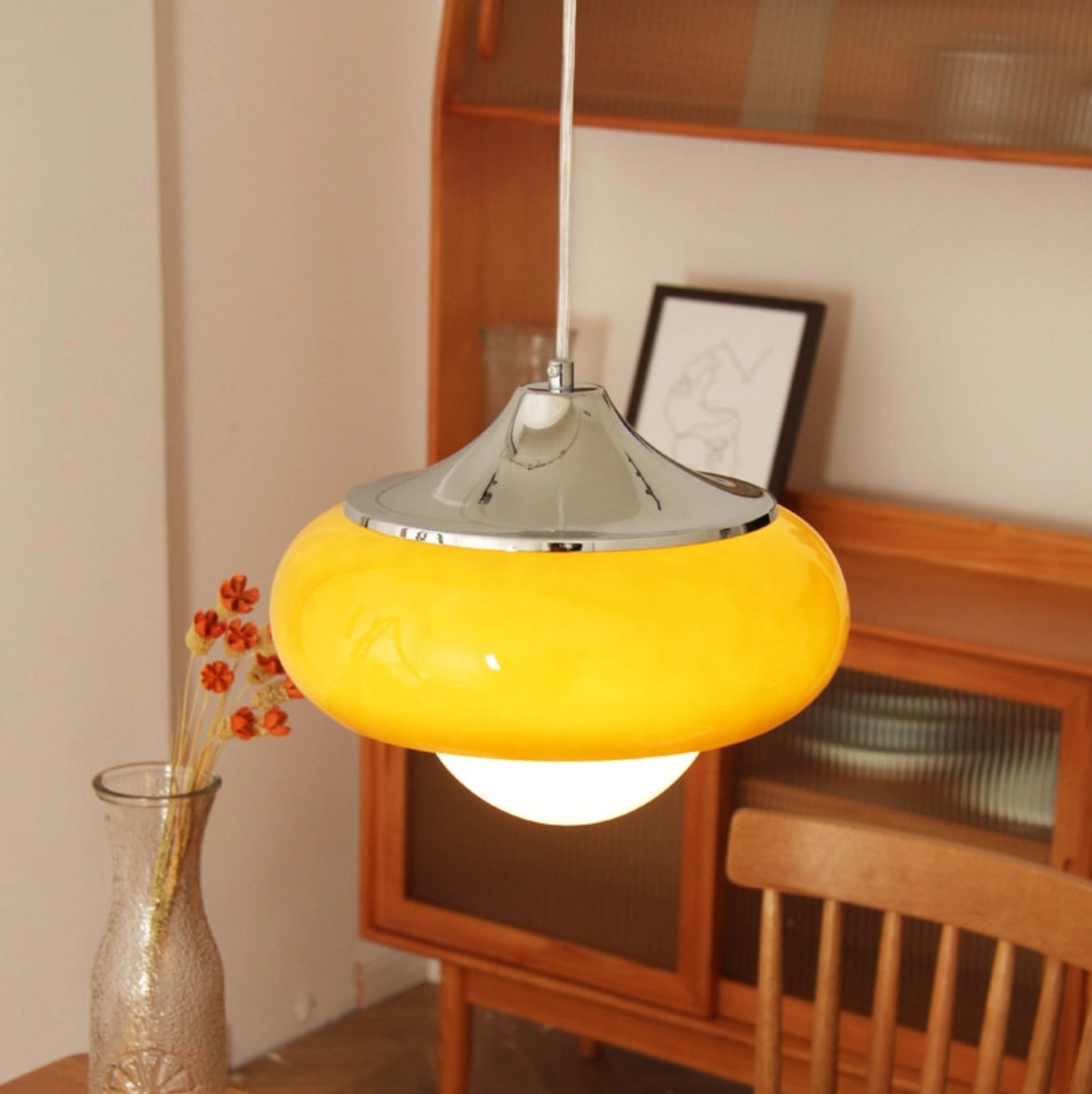 Modern dual color pendant lamps in Scandinavian mid-century style with wooden accents, featuring an orange shade, hanging from the ceiling in a stylish interior setting.