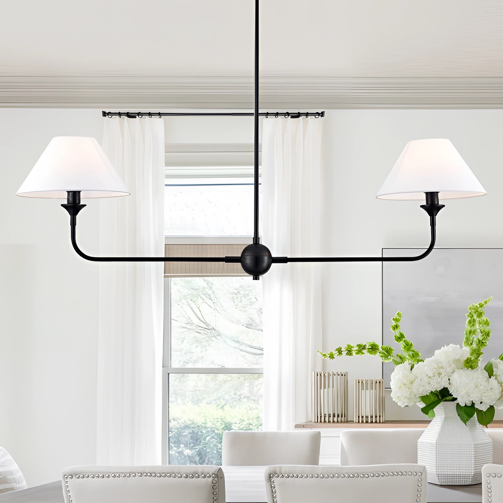 Modern dual lamp black LED chandelier with double cone pendant light design hanging from the ceiling in a stylish interior. The room features wood accents, a grey table, shelving, and a potted plant, highlighting contemporary furniture and design elements.
