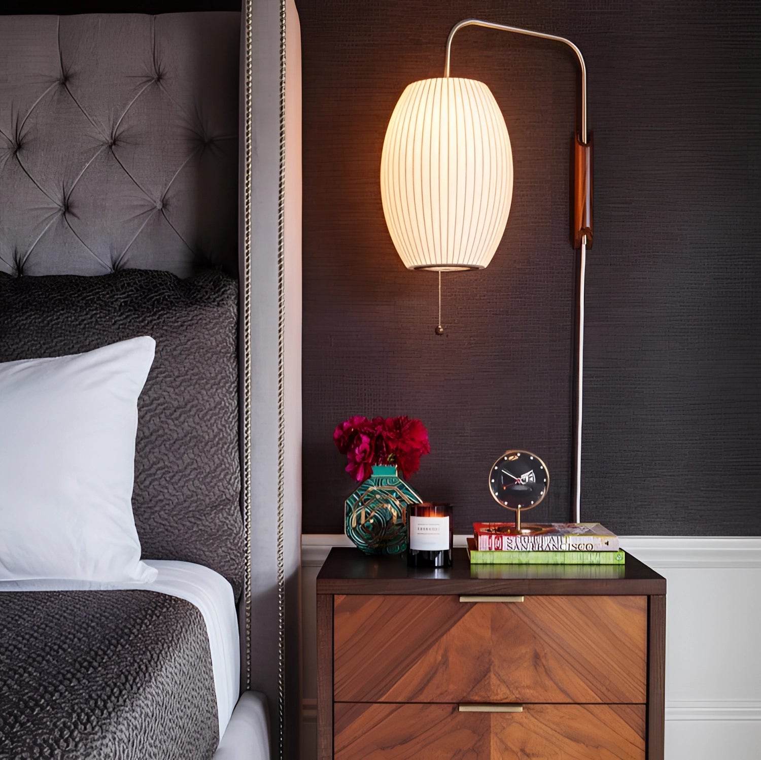 Modern floor lamp with a minimalist design featuring adjustable brass and wood accents, positioned in an interior setting with warm orange lighting and complementing textile elements.