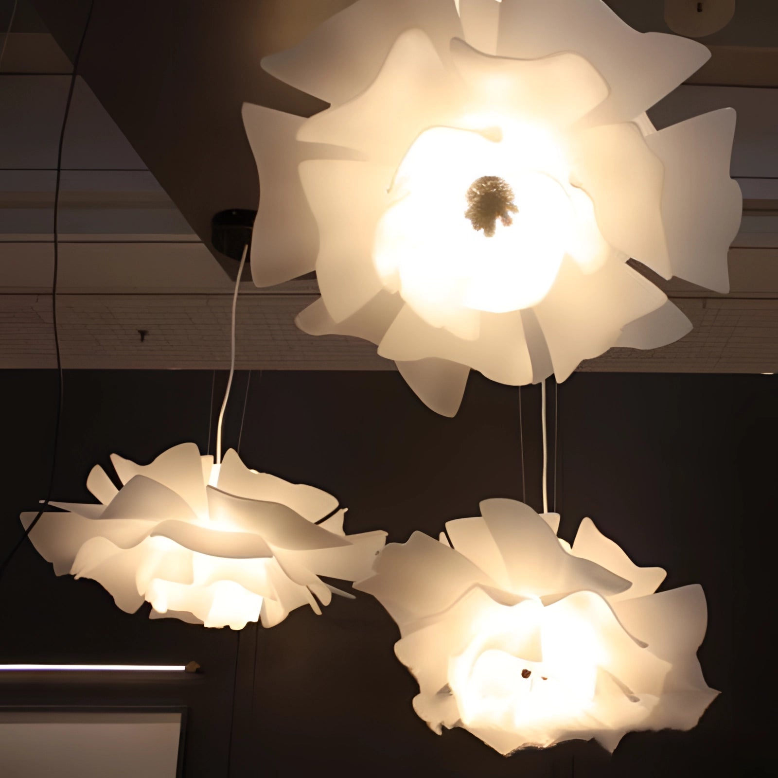 A modern flower-shaped pendant light with white petals and a black center, featuring a symmetrical, artistic design and stylish lighting shade.