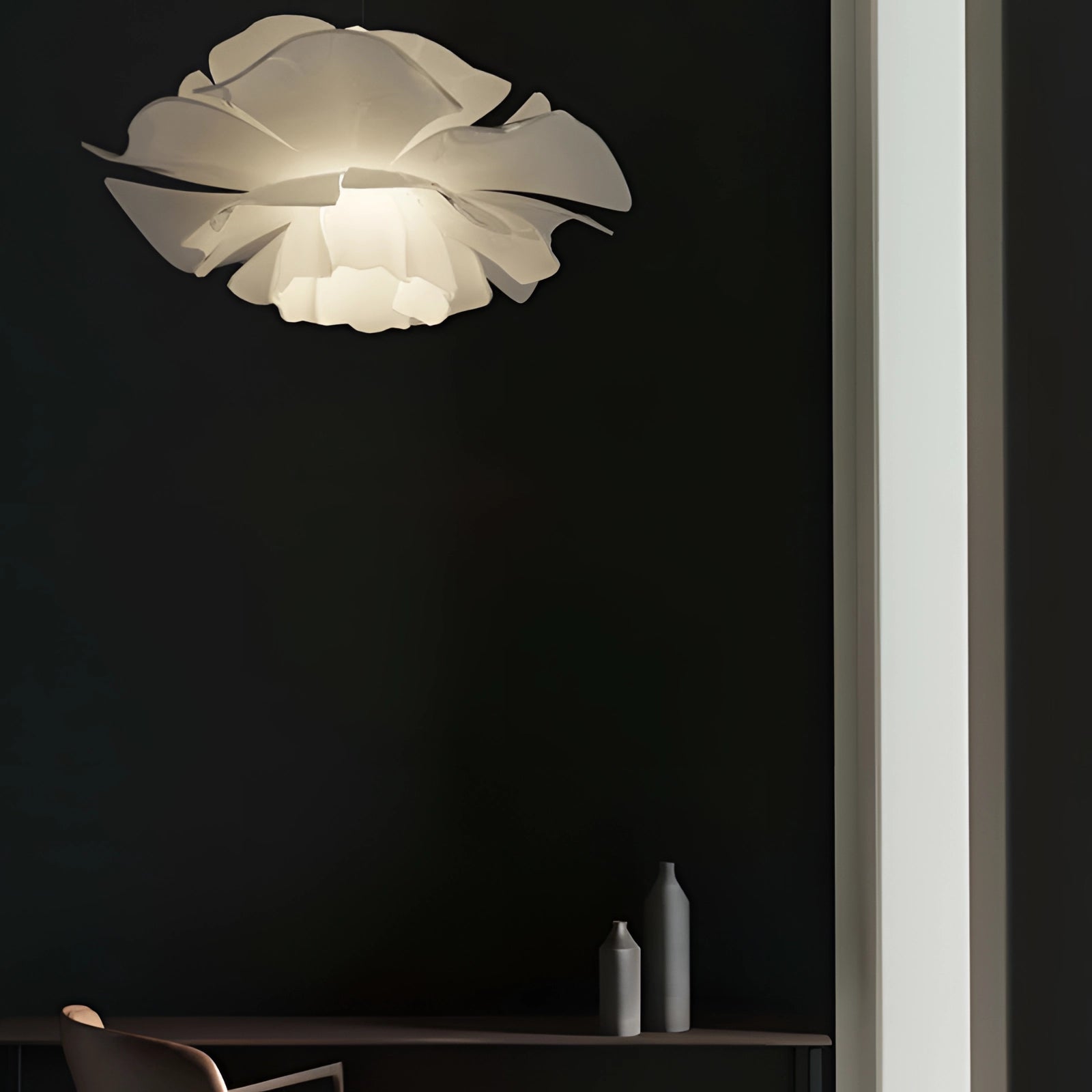 Modern flower-shaped pendant light with black petals and wooden accents against a blue sky background.