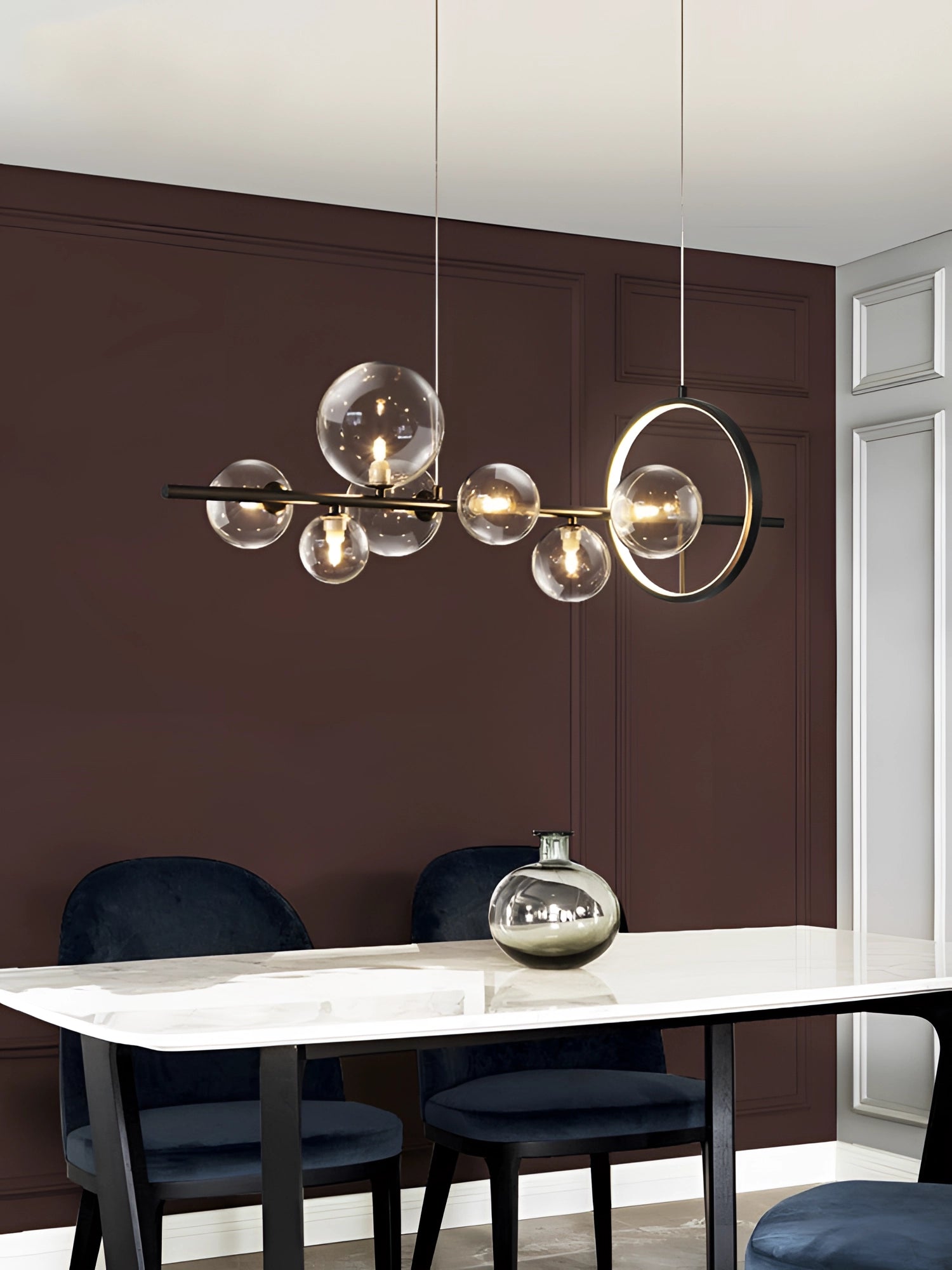 Modern geometric brass and glass chandelier hanging over a wooden table in a stylish interior setting with white walls.