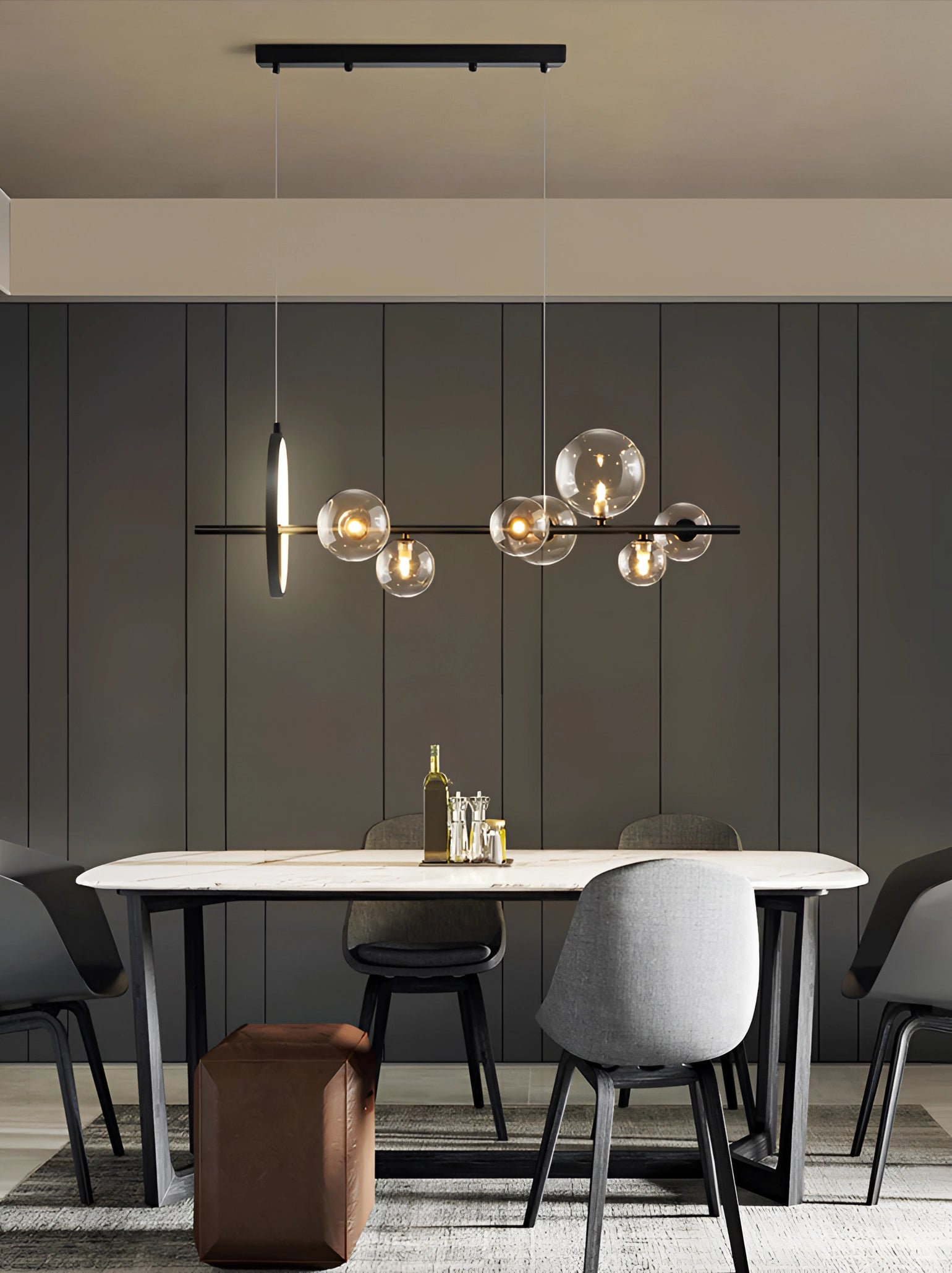 A modern geometric brass and glass chandelier hangs above a wooden table and chairs in a stylishly designed interior with beige walls and flooring.