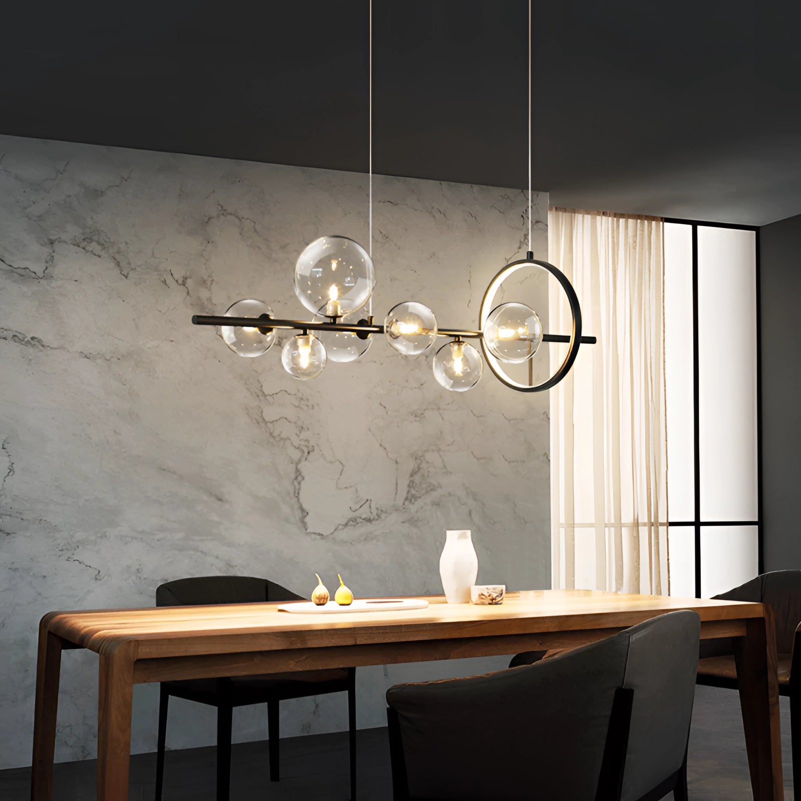 Modern geometric brass and glass chandelier hanging over a wooden table in an elegant interior design setting.