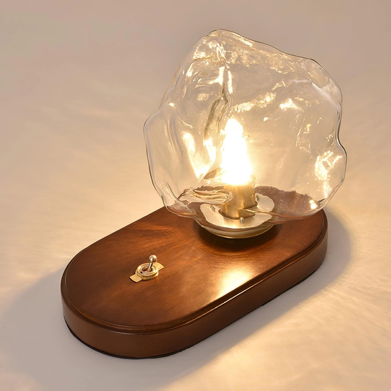 Modern geometric glass desk lamp with a wooden base, featuring amber glass and metal elements, captured in still life photography.