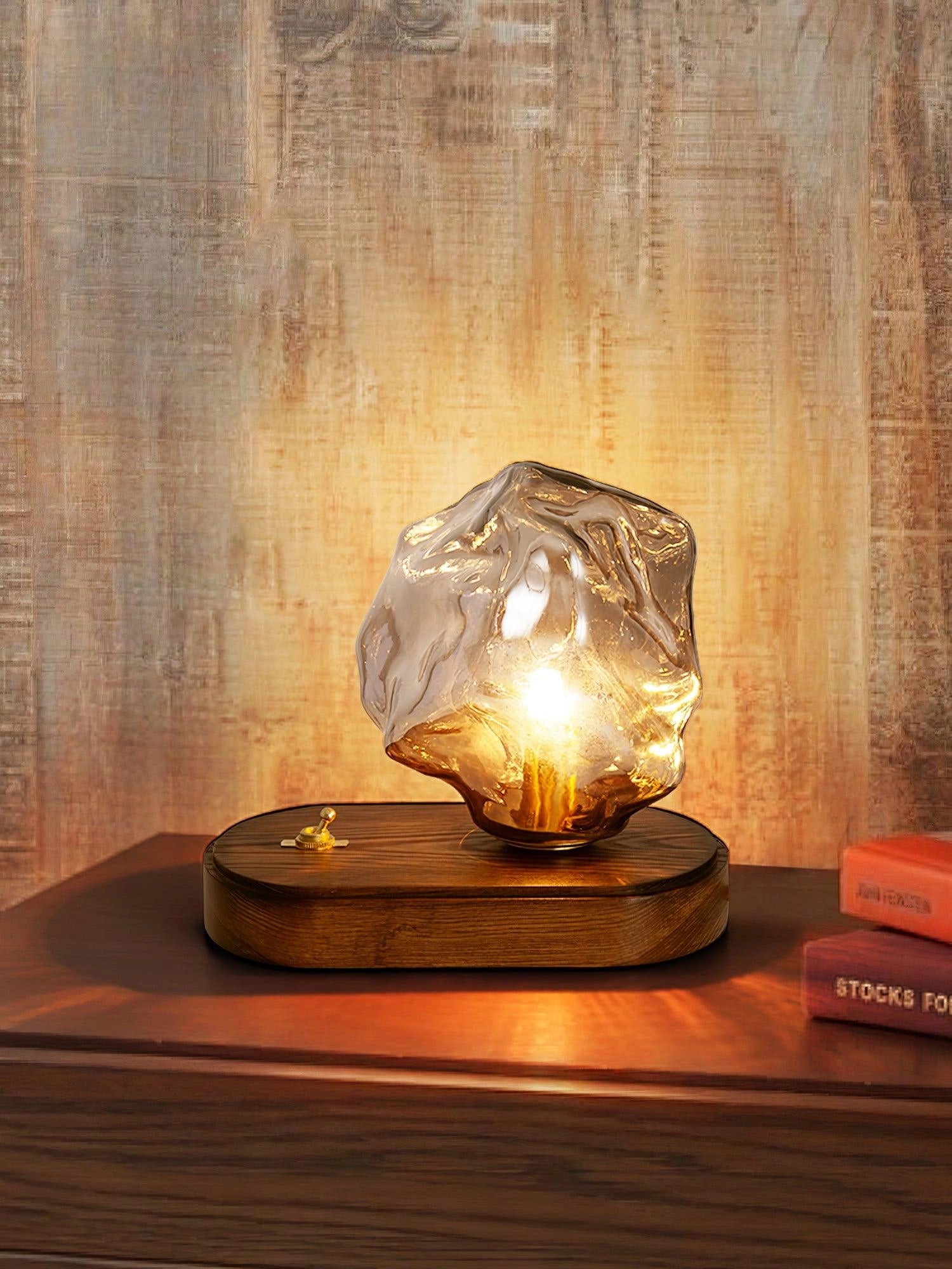 Modern geometric glass desk lamp with amber glow, wooden base, and artistic design.