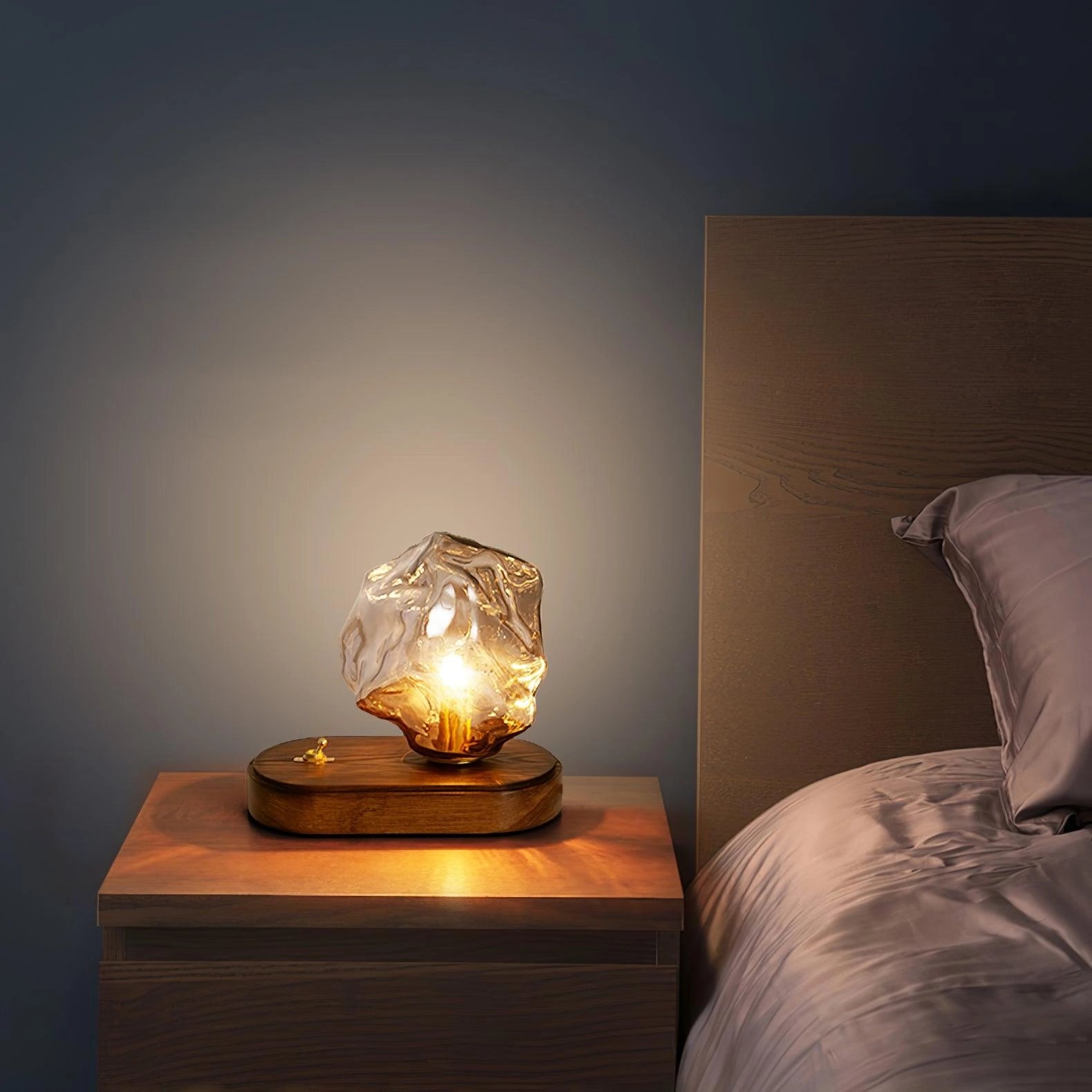 Modern geometric glass desk lamp with a wooden base, featuring an amber-tinted glass shade, illuminating a cozy and artistic interior setting.