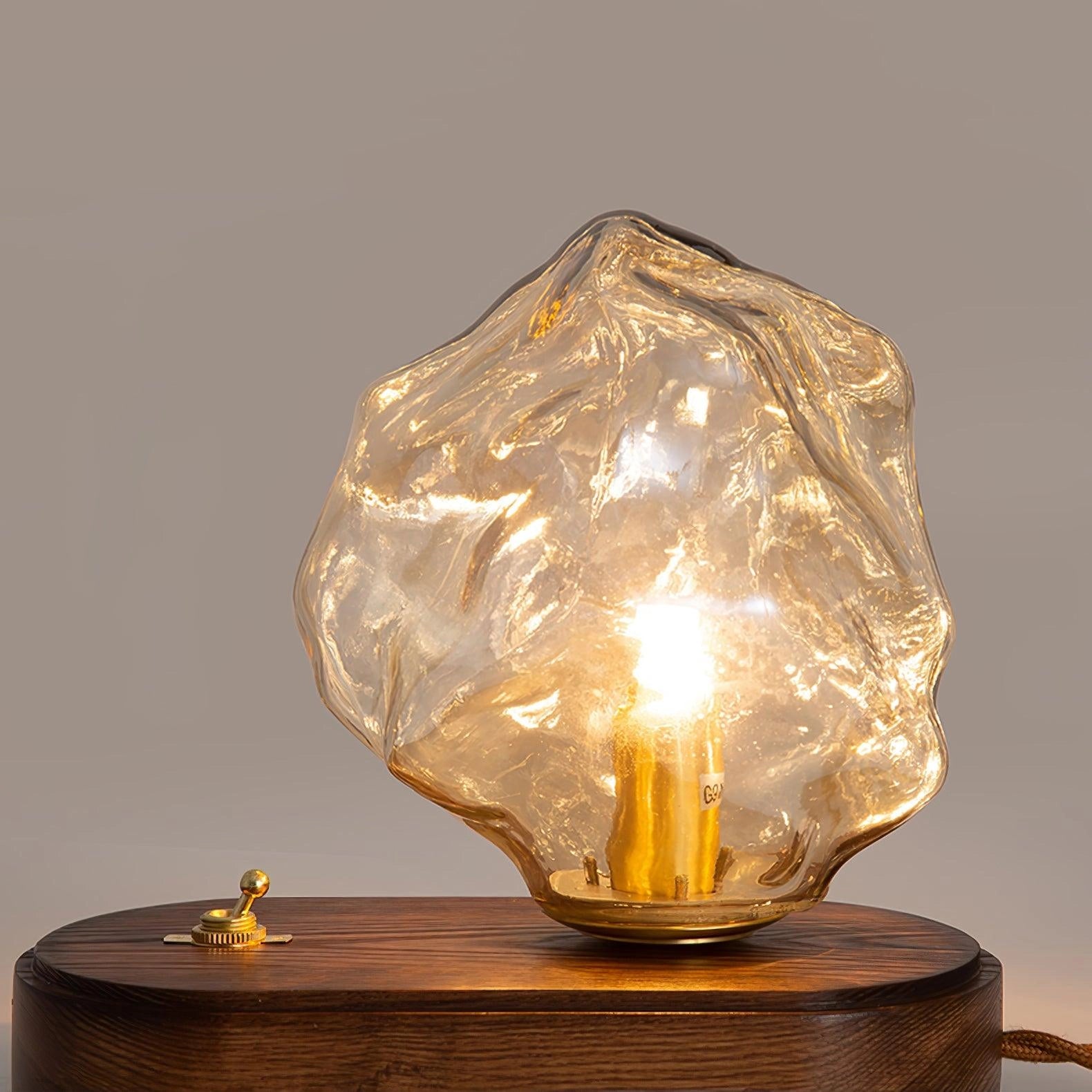 Modern geometric glass desk lamp with wooden base featuring amber light and artistic design.
