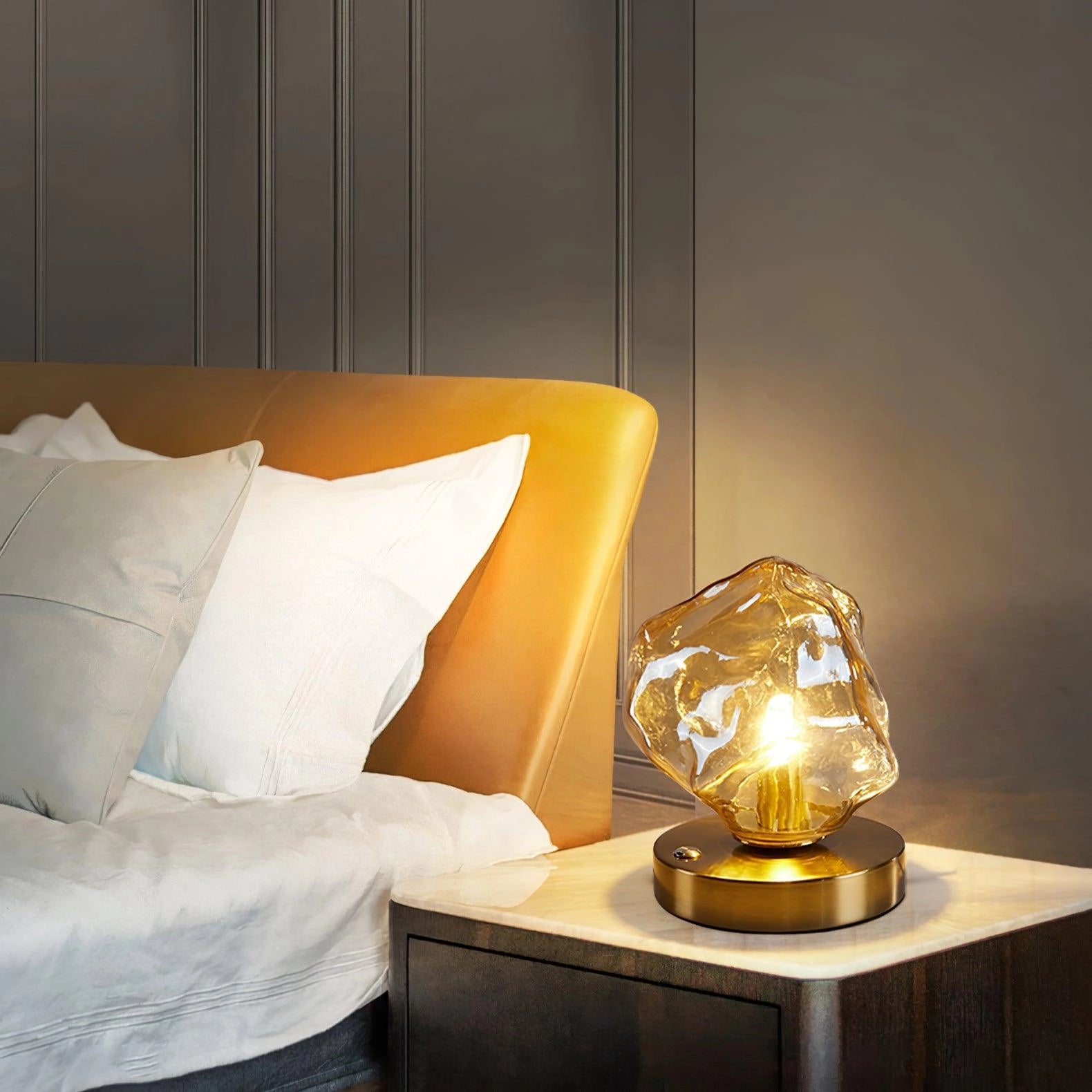 Modern geometric glass desk lamp with a wooden base placed on a wooden table.