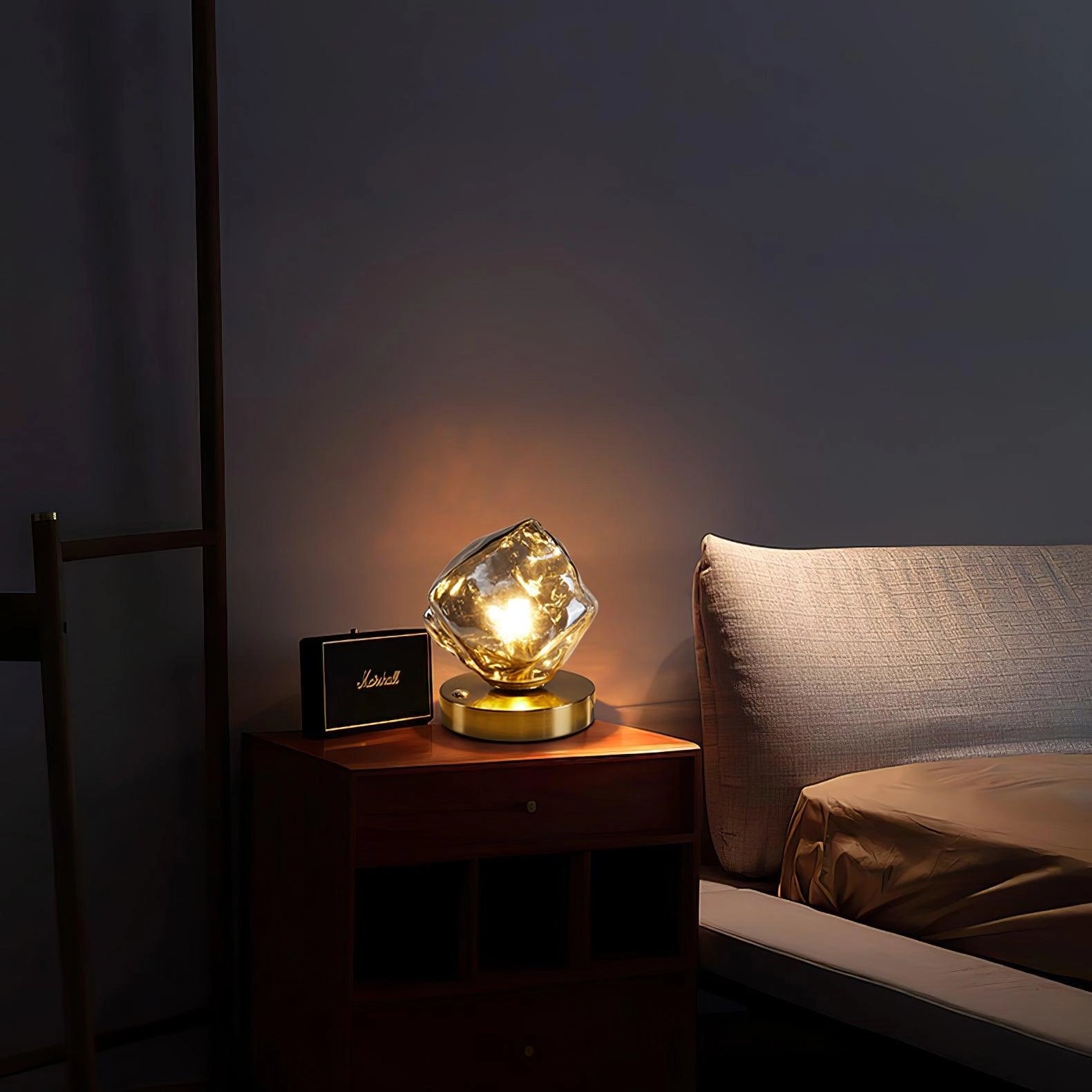 Modern geometric glass desk lamp with a wooden base placed on a table in a stylish living room, next to a couch, showcasing contemporary interior design.