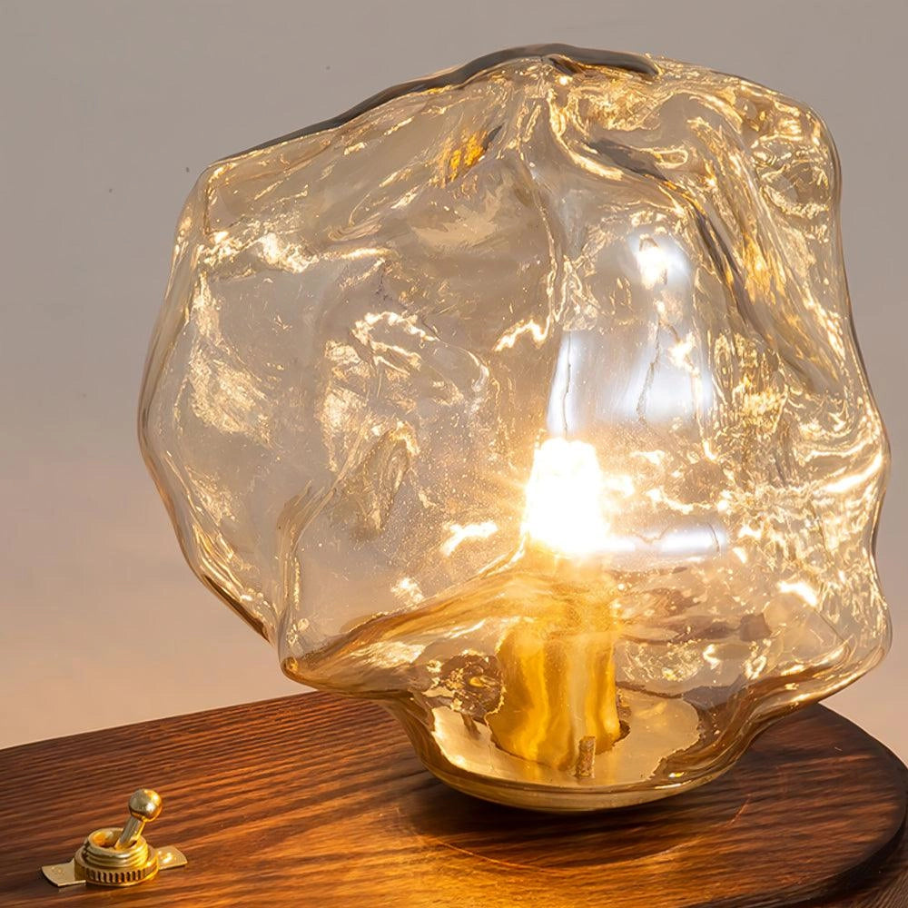 Modern geometric glass desk lamp with a wooden base featuring an amber and yellow glass shade, artistic design, and metal accents.