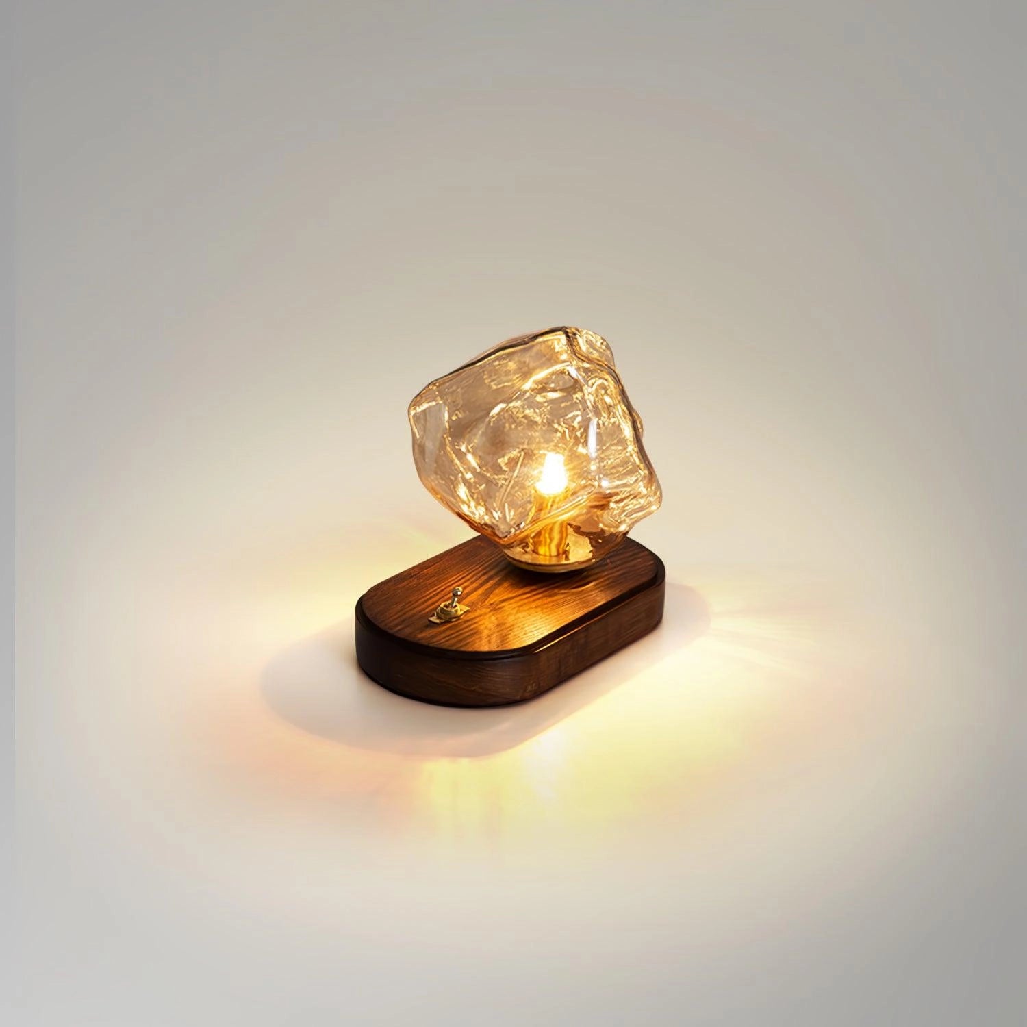 A modern geometric glass desk lamp with an amber glass shade and a wooden base, featuring gold metal accents in a rectangular design.