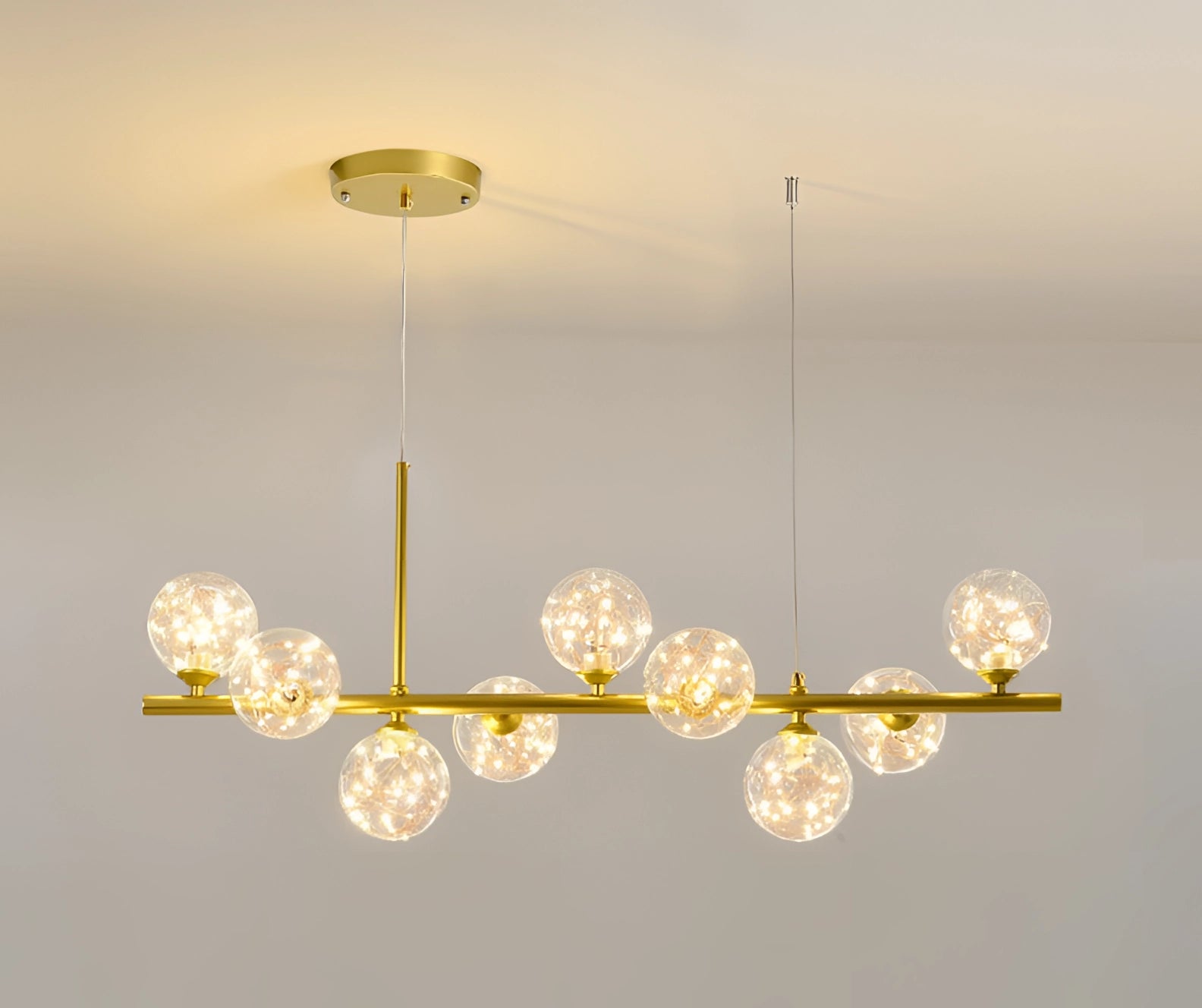 Modern Glass Globe Chandelier with Adjustable Bronze Pendant Light in Gold Shimmering Finish, featuring amber-tinted glass globes and twig-like accents, illuminating a ceiling space with artistic elegance.