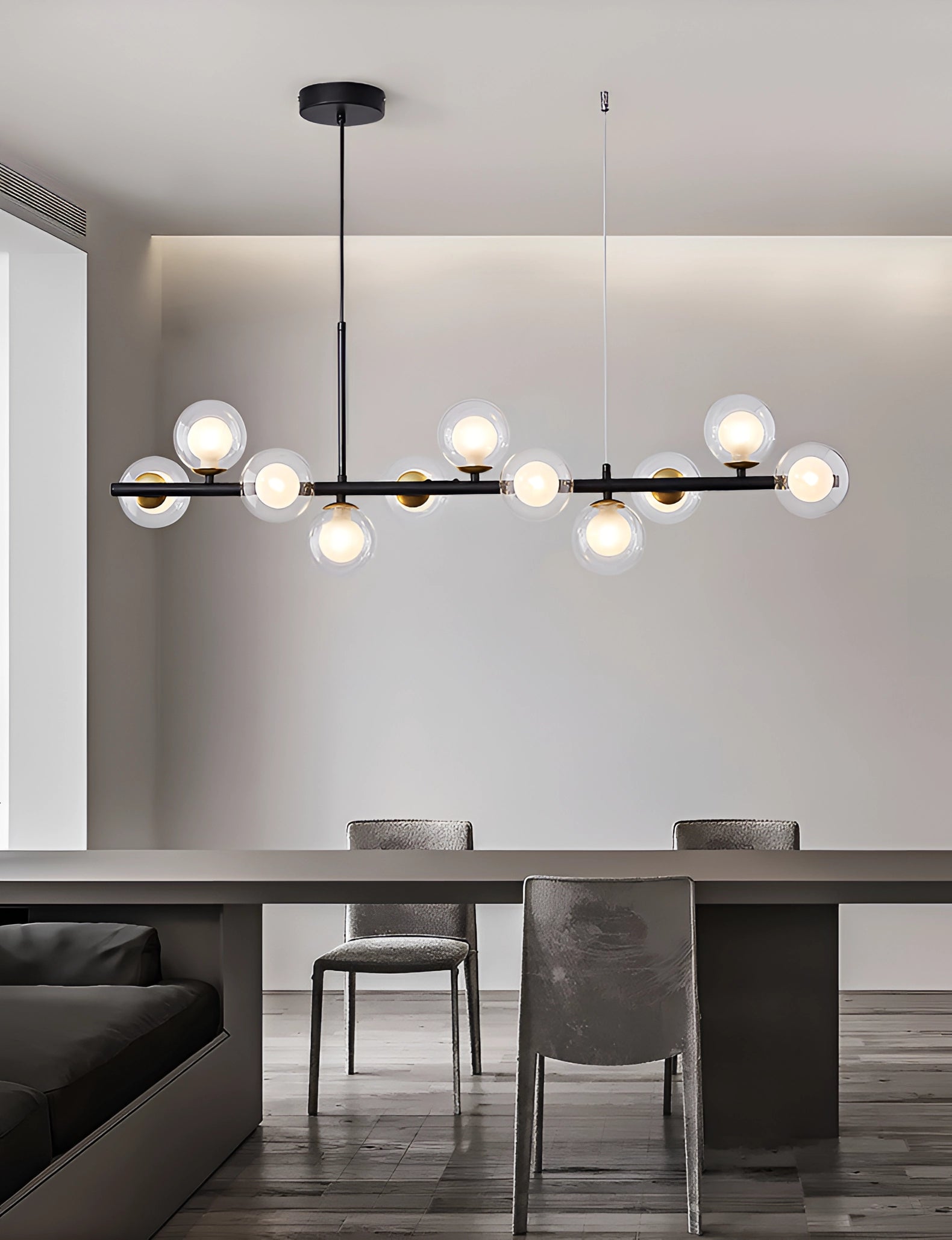 Modern glass globe chandelier with adjustable bronze pendant light fixture hanging in a stylish interior setting featuring white walls, wooden furniture, and a cozy couch.