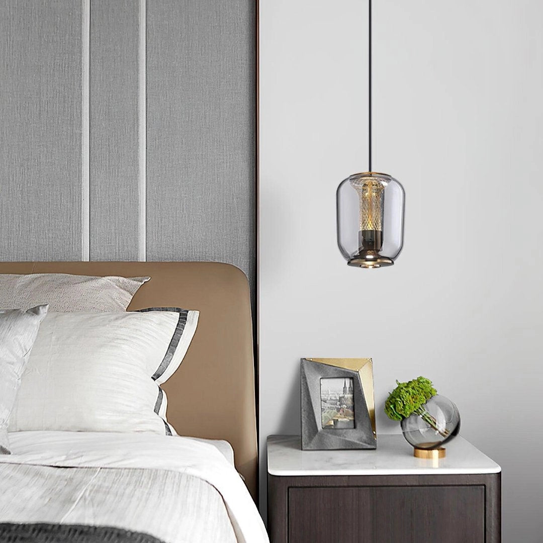 Modern Glass LED Pendant Light hanging above a minimalist bedroom setting featuring a bed with plush pillows, wooden elements, and ample natural light from large windows.