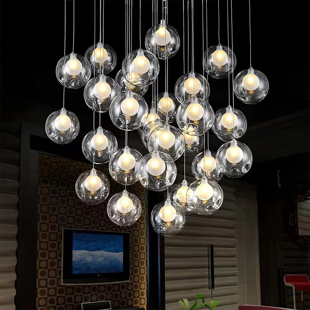 Modern globe pendant chandelier with adjustable LED lights, featuring a square ceiling plate and 25 lights, suspended in an elegant arrangement. The fixture is set against a stylish interior design with decorative elements, including a plant and wall ornamentation.