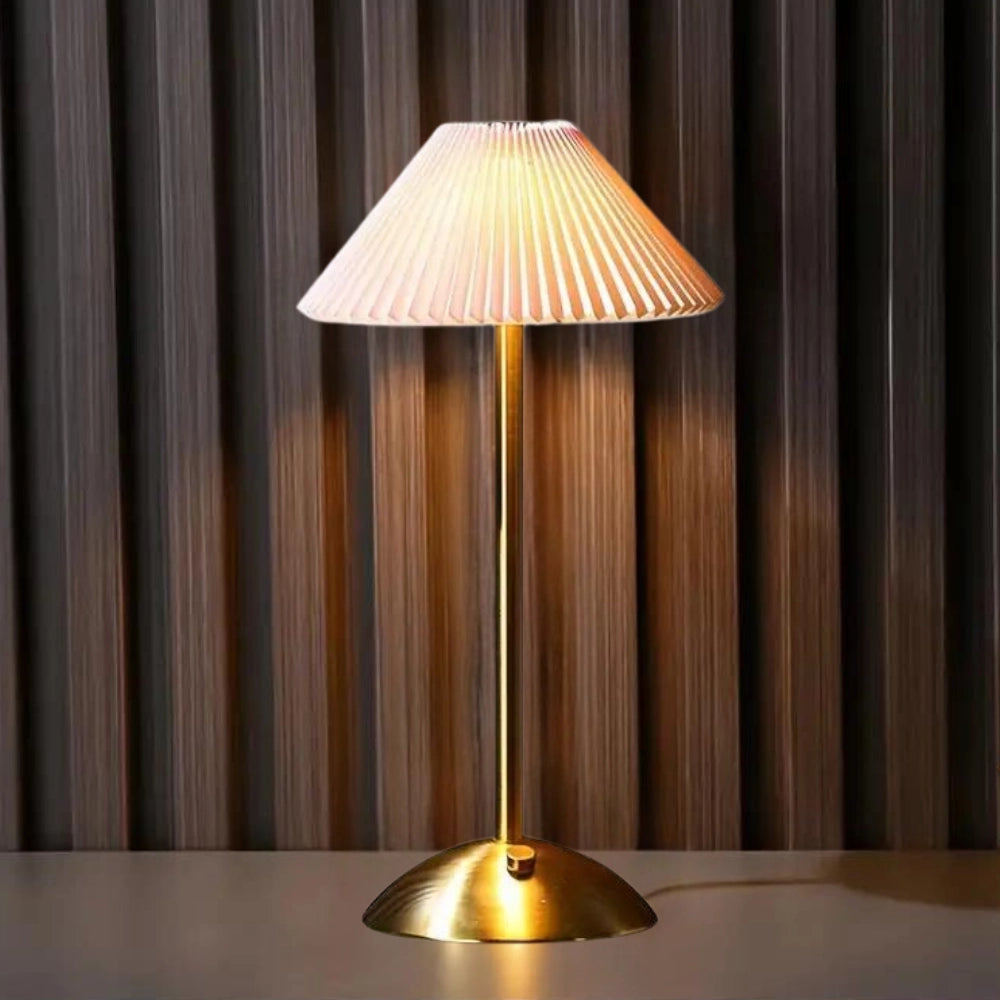 Modern gold base table lamp with an elegant ribbed pleated pink lampshade, designed for interior use.