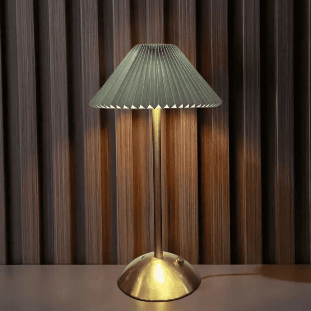 A modern table lamp featuring a gold base and an elegant ribbed pleated lampshade in green, designed for interior lighting and decor.