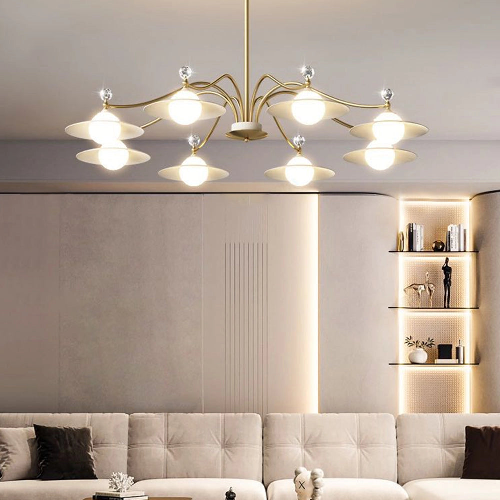Modern gold chandelier featuring eight white glass globes with a brass finish, hanging in a stylish interior setting with a beige couch and wooden accents.