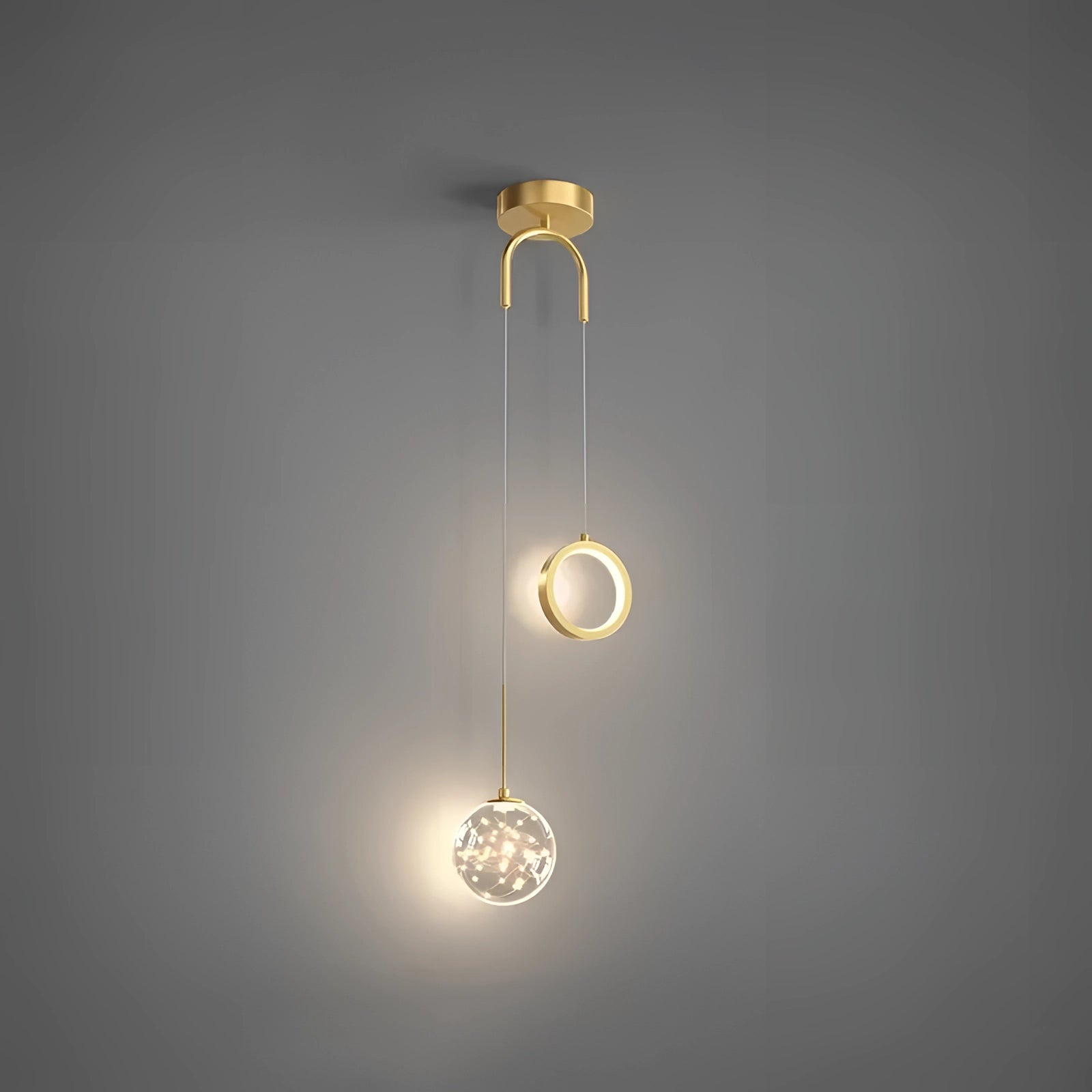 Modern gold dual pendant light ceiling fixture with an adjustable design, featuring two circular metal shades, suspended against a dark background.