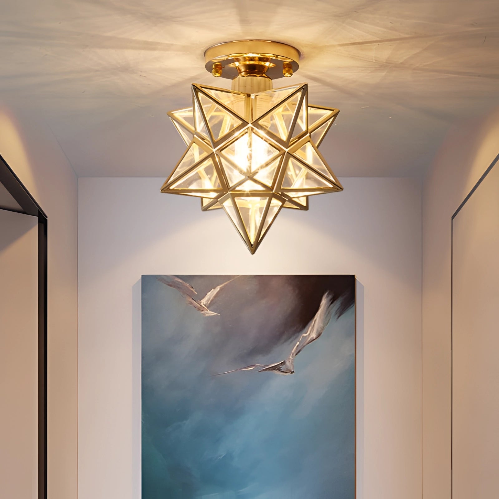 Modern gold geometric star ceiling light with transparent glass panels, featuring a luxurious pendant lamp design. The light has an artful geometric structure, resembling a star, and offers a warm amber glow, suitable for stylish interiors.
