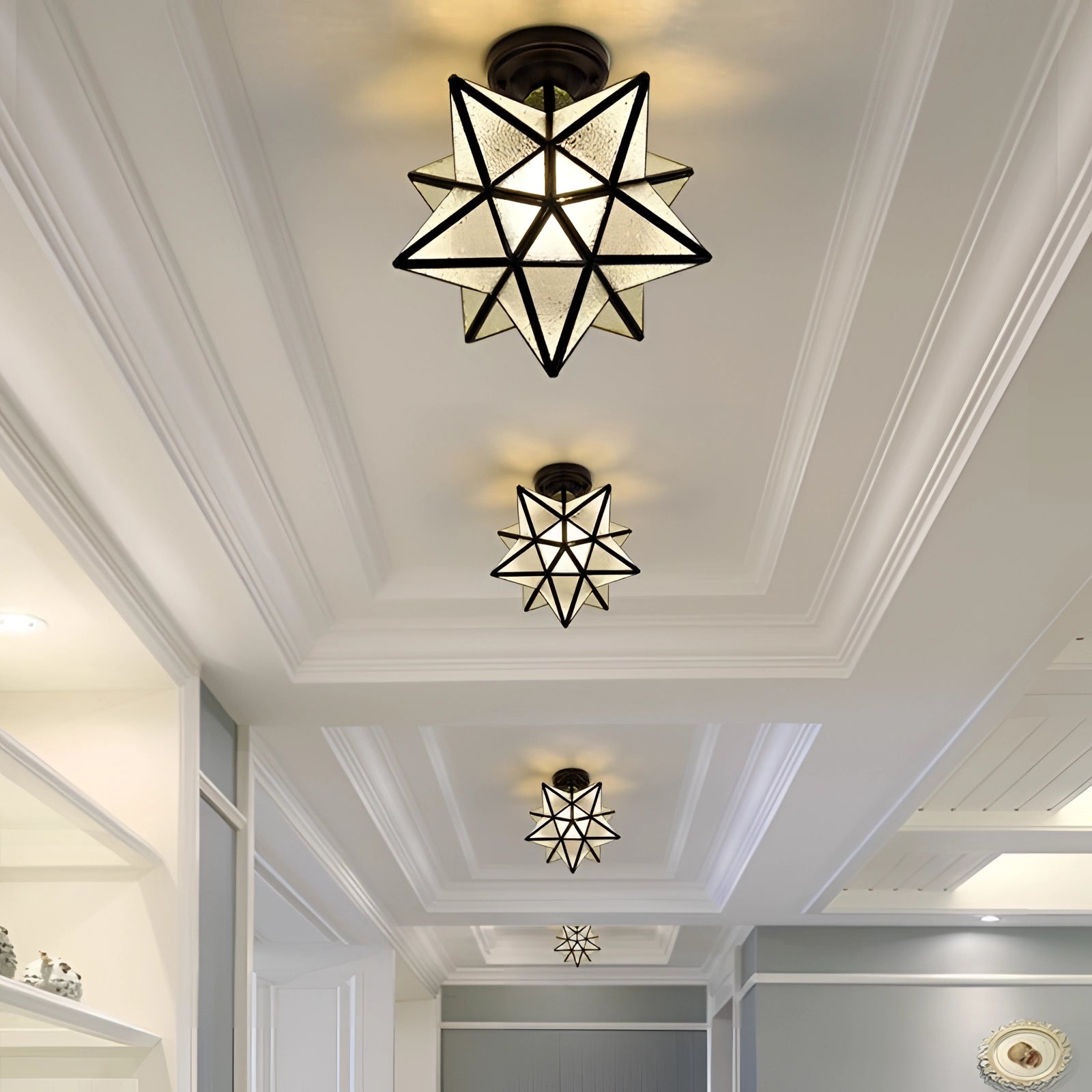 Modern gold geometric star ceiling light with black and frosting accents, featuring a sleek design and symmetrical lines, hanging from a ceiling and illuminating the space with a warm glow.