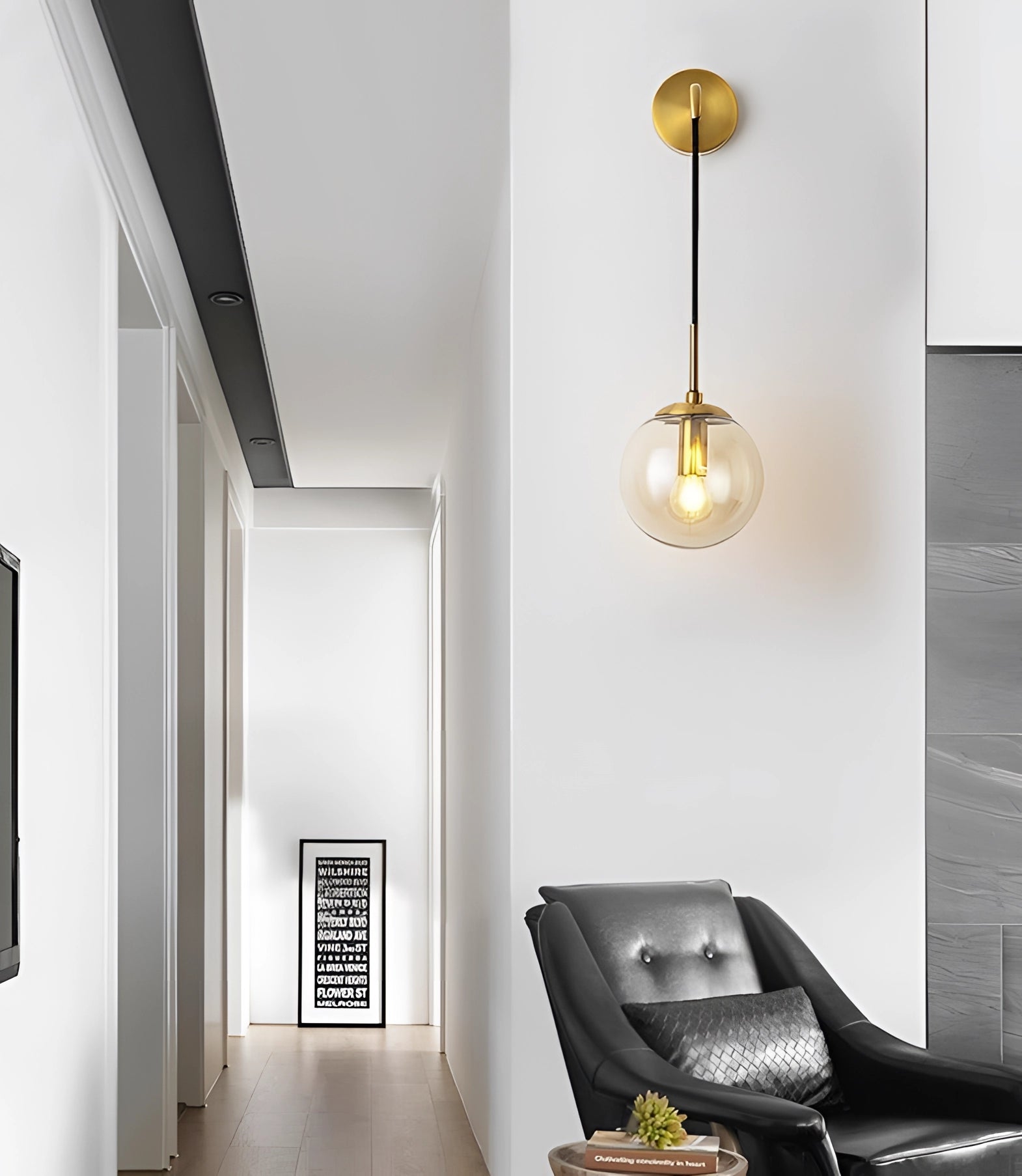 Modern gold globe wall sconce with a brass finish and glass orb design mounted on a grey wall, enhancing the interior decor with soft lighting.