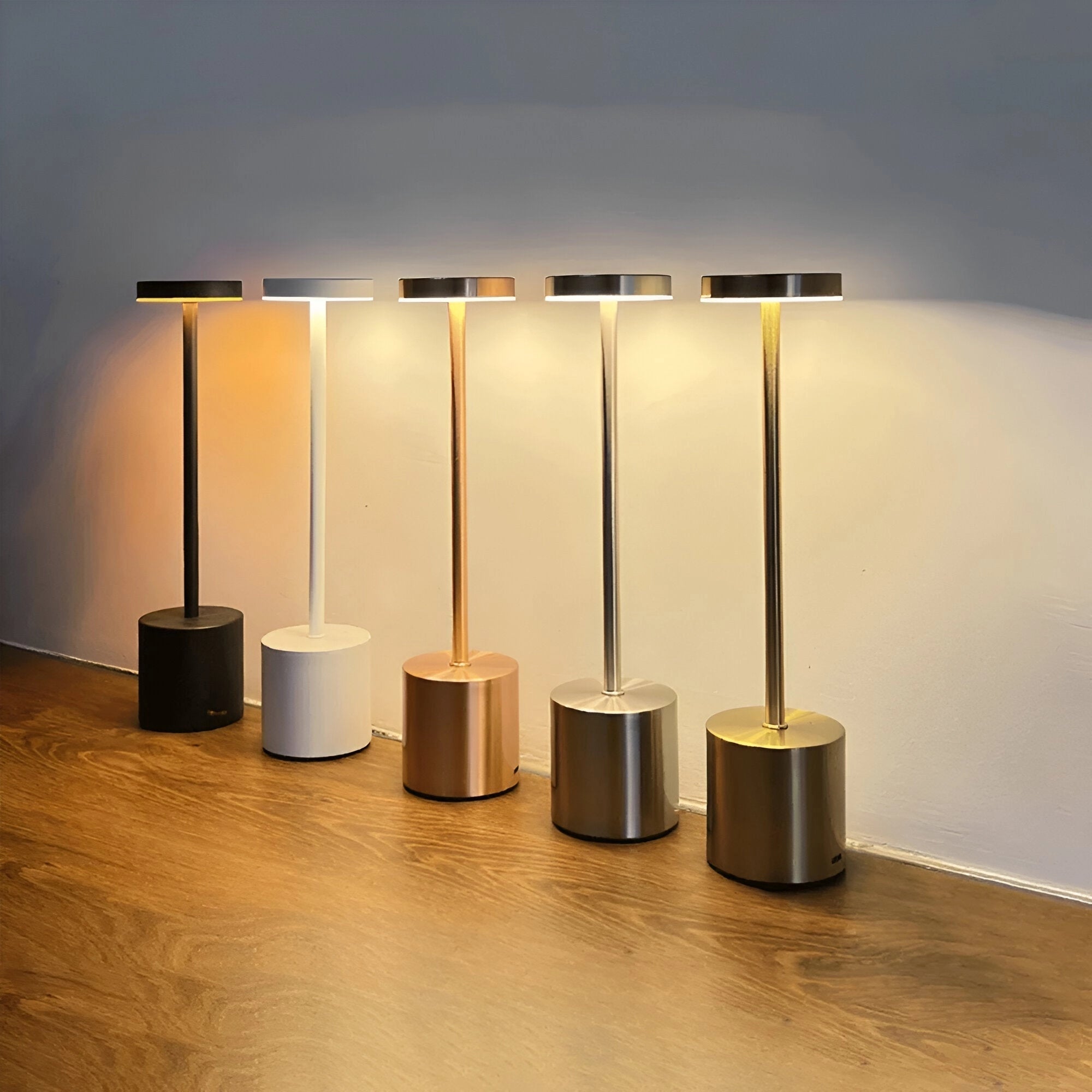 Modern gold LED desk lamp with an adjustable brightness feature, showcasing a sleek cylindrical design. The lamp, finished in a white variant, is placed on a wooden surface that highlights its contemporary and elegant appearance.