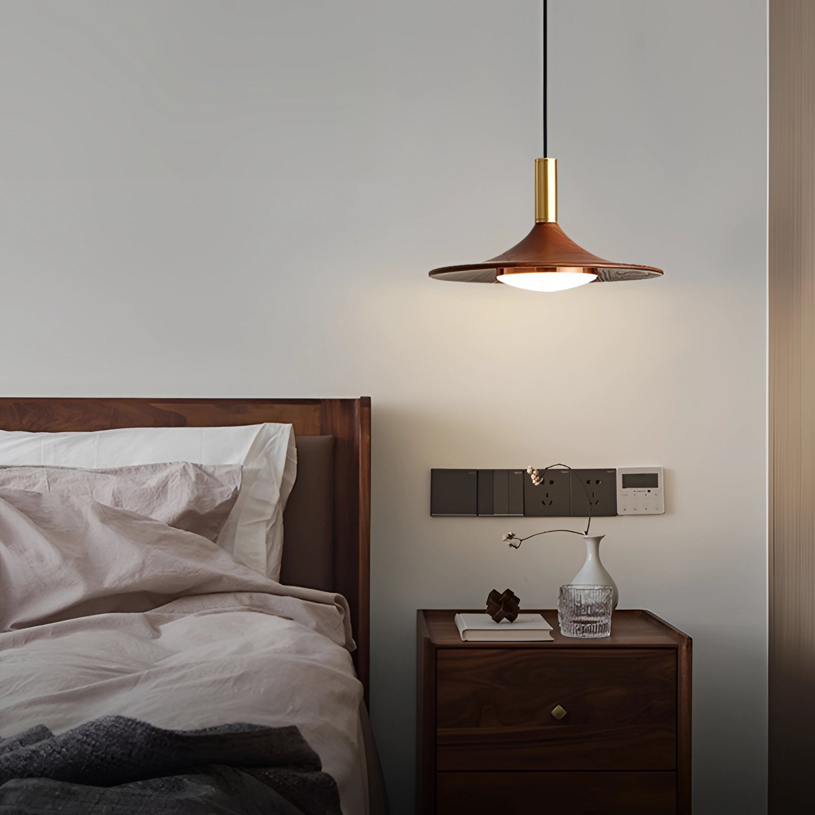 Modern gold LED pendant light fixture hanging in a Scandinavian-style interior with white walls, wooden cabinetry, hardwood flooring, and minimalist design elements.