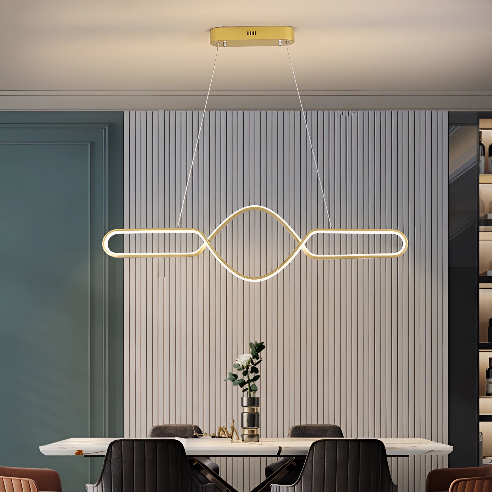 Modern gold LED pendant light with a luxurious adjustable infinity design, shown hanging in an elegantly designed interior space with contemporary furniture, including a chair and table, emphasizing the chic architectural elements and warm ambiance.
