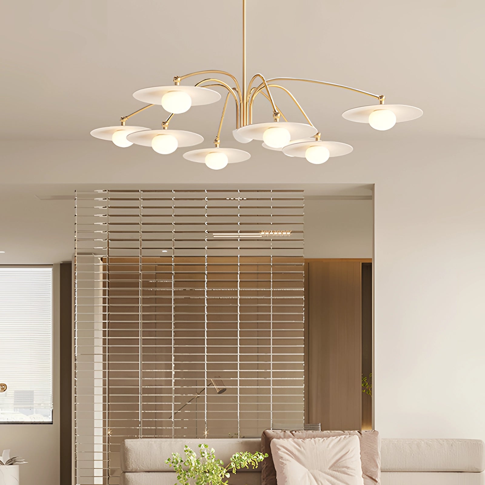 Modern gold opal glass mid-century chandelier hanging in a stylish interior space, with natural light filtering through large windows, complemented by wooden flooring and houseplants.