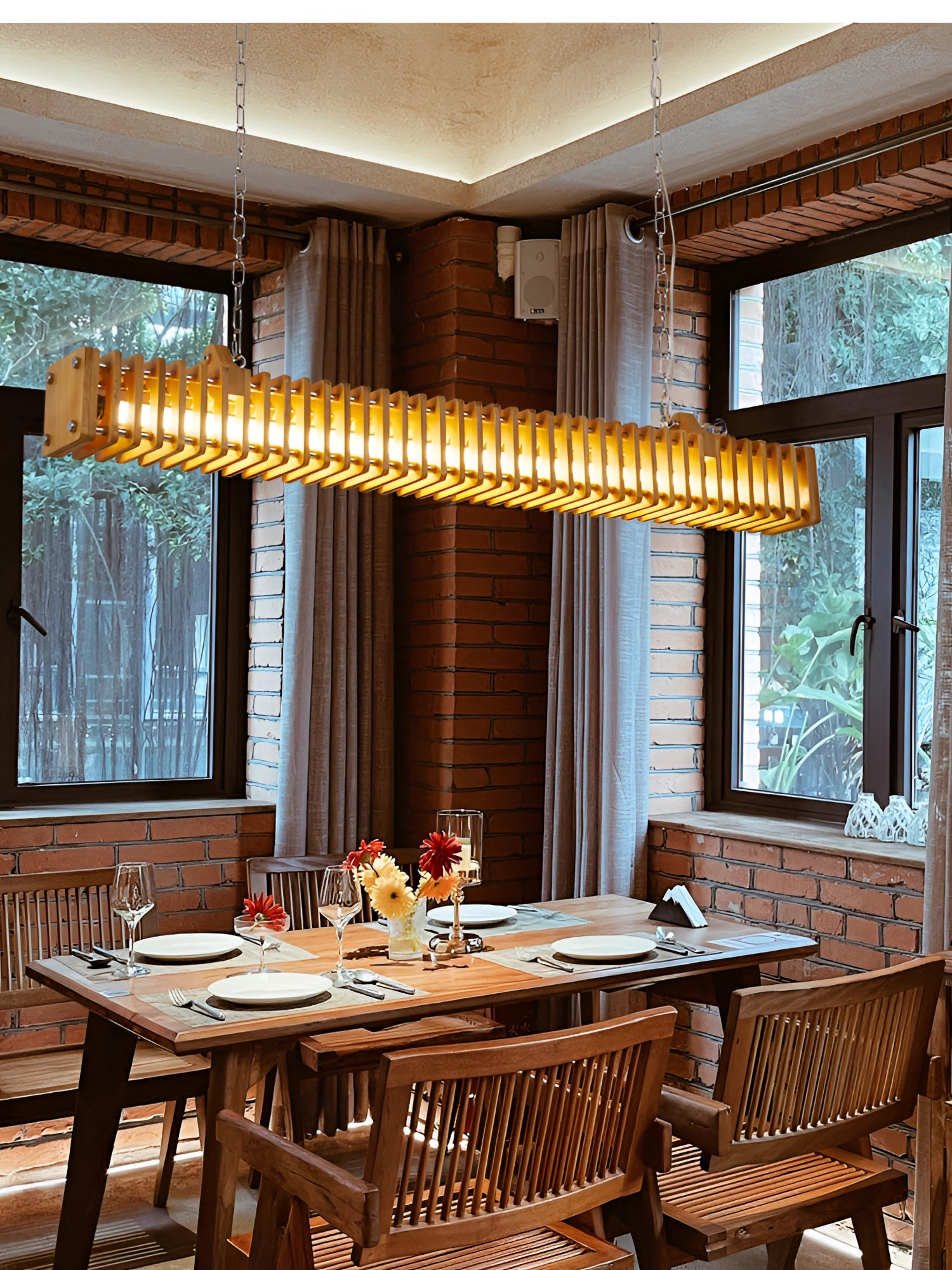 Modern gold pendant light hanging over a wooden table in a stylishly decorated interior with curtains and chairs.