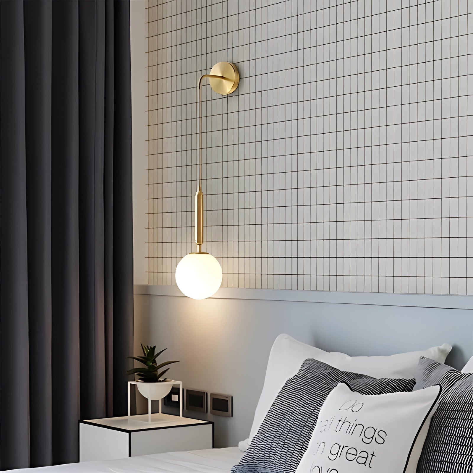Modern gold wall lamp with an adjustable LED sconce and brass finish mounted on a wall, illuminated in a stylish interior setting with wooden flooring and plants.