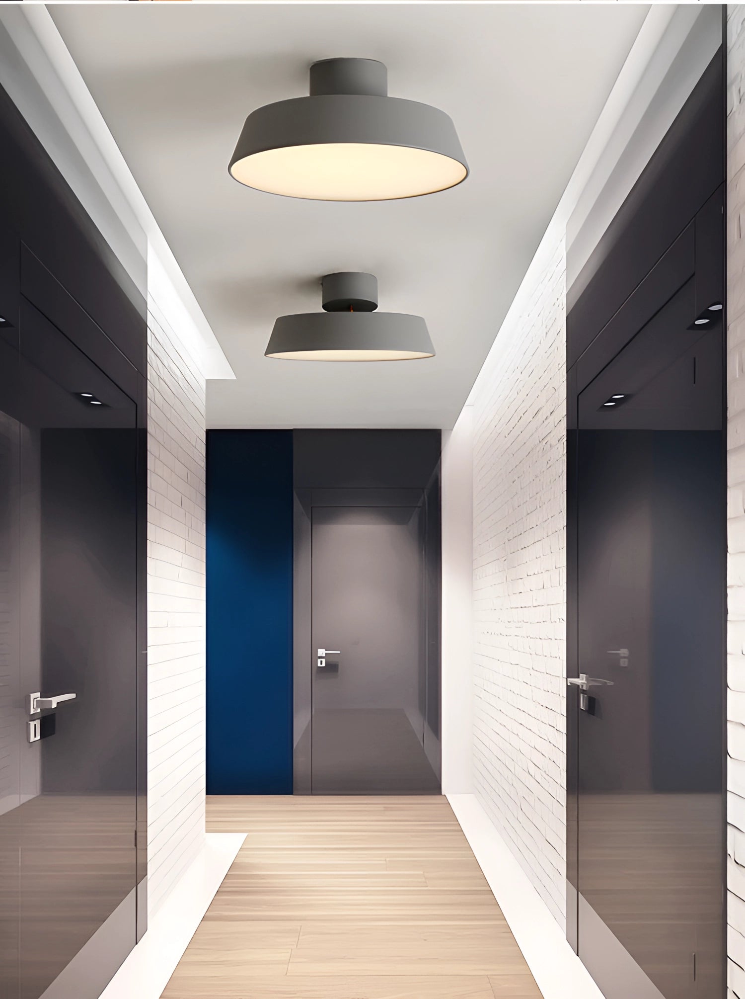 Modern grey LED pendant light with minimalist industrial design, hanging from a ceiling in a stylish interior with wooden flooring and doors.