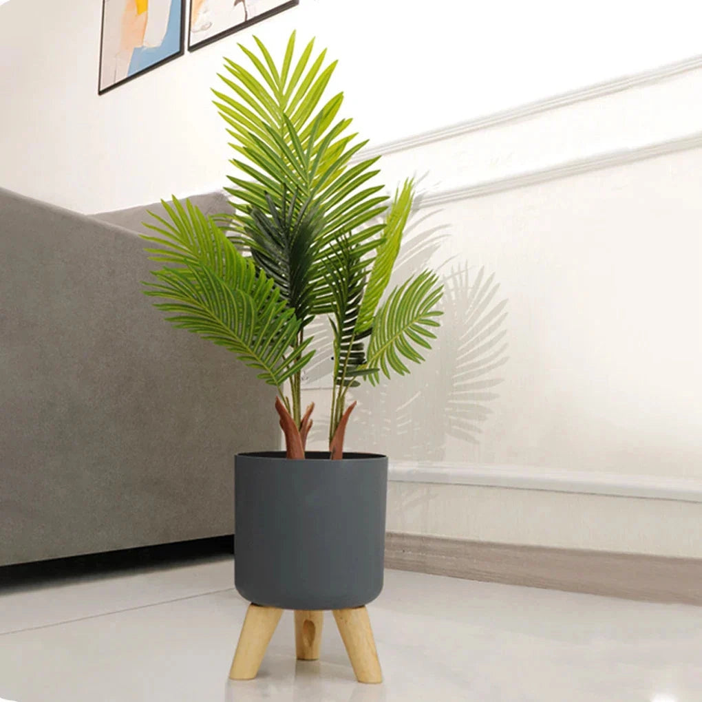 Modern ice bucket with stand featuring wooden legs, placed in a stylish interior setting beside a window, complemented by houseplants and wooden flooring.