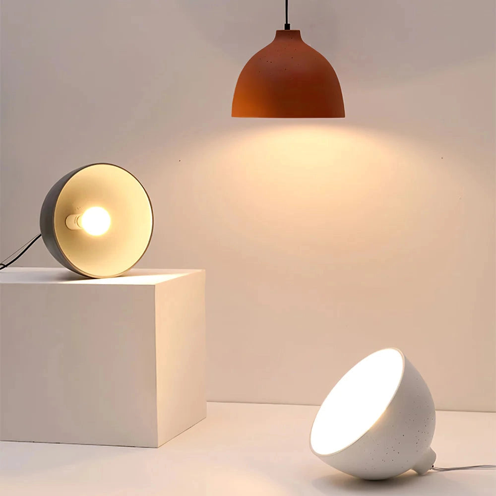 Modern industrial pendant light with a Scandinavian design, featuring a concrete finish and a yellow accent. The light has an orange tint and measures 11 inches in diameter. It is suspended from the ceiling, complementing the interior design with its circular form and subtle wood elements.