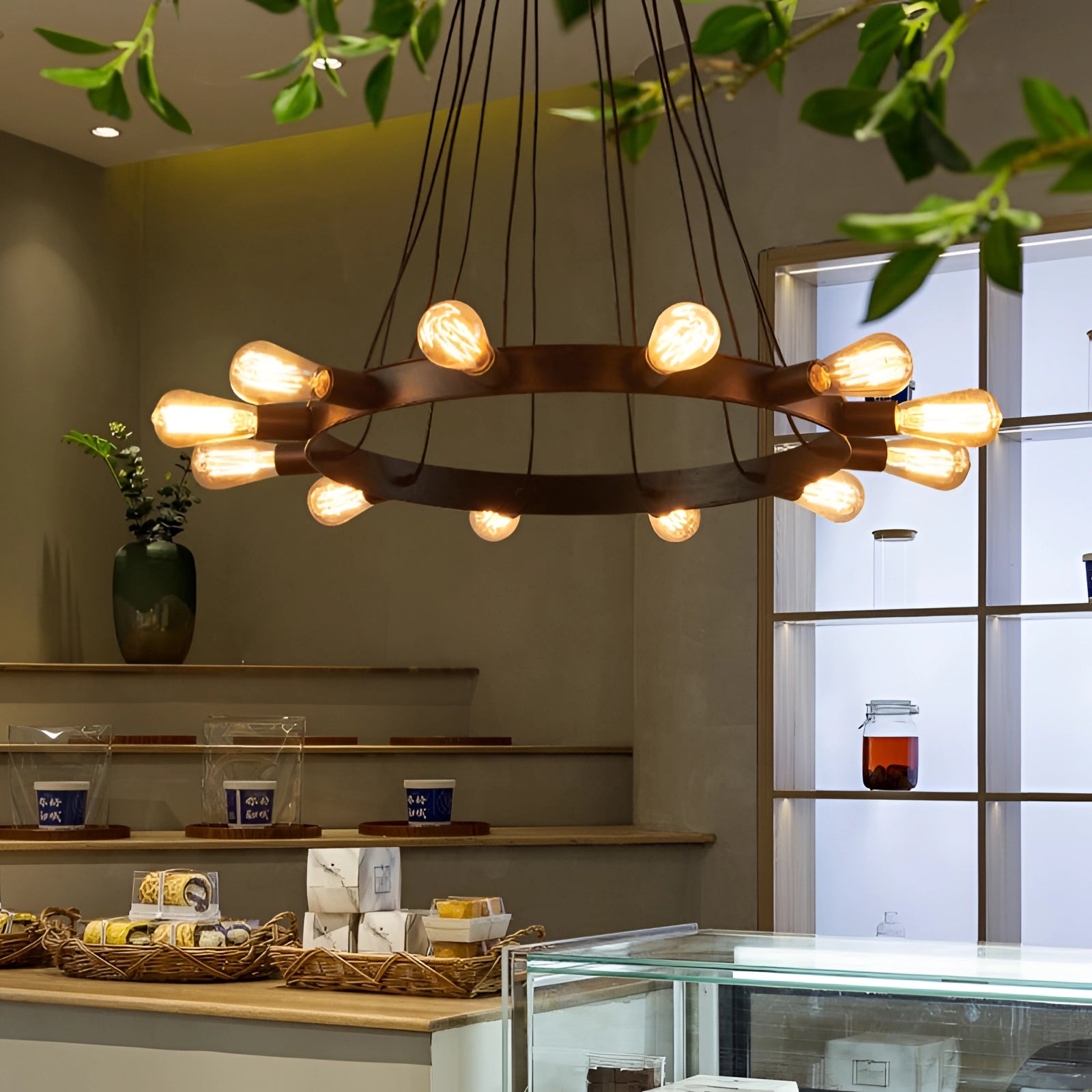 Modern industrial circular LED chandelier hanging from the ceiling, illuminating a stylish kitchen with wood cabinetry and a sleek countertop.