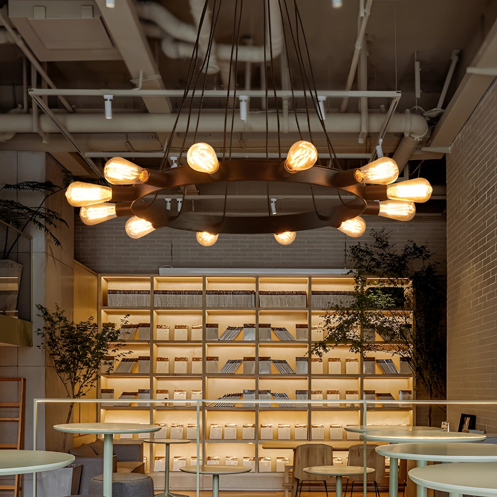 Modern industrial LED chandelier with a circular design, featuring a sleek metallic finish, hanging from the ceiling in a stylishly furnished room. The space includes a wooden coffee table, potted plant, and contemporary interior decor elements, emphasizing a blend of industrial and natural aesthetics.