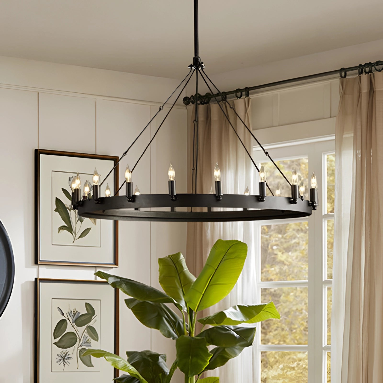 Modern industrial round iron chandelier with 18 lights hanging in a stylish dining room featuring houseplants, wooden elements, and framed pictures.