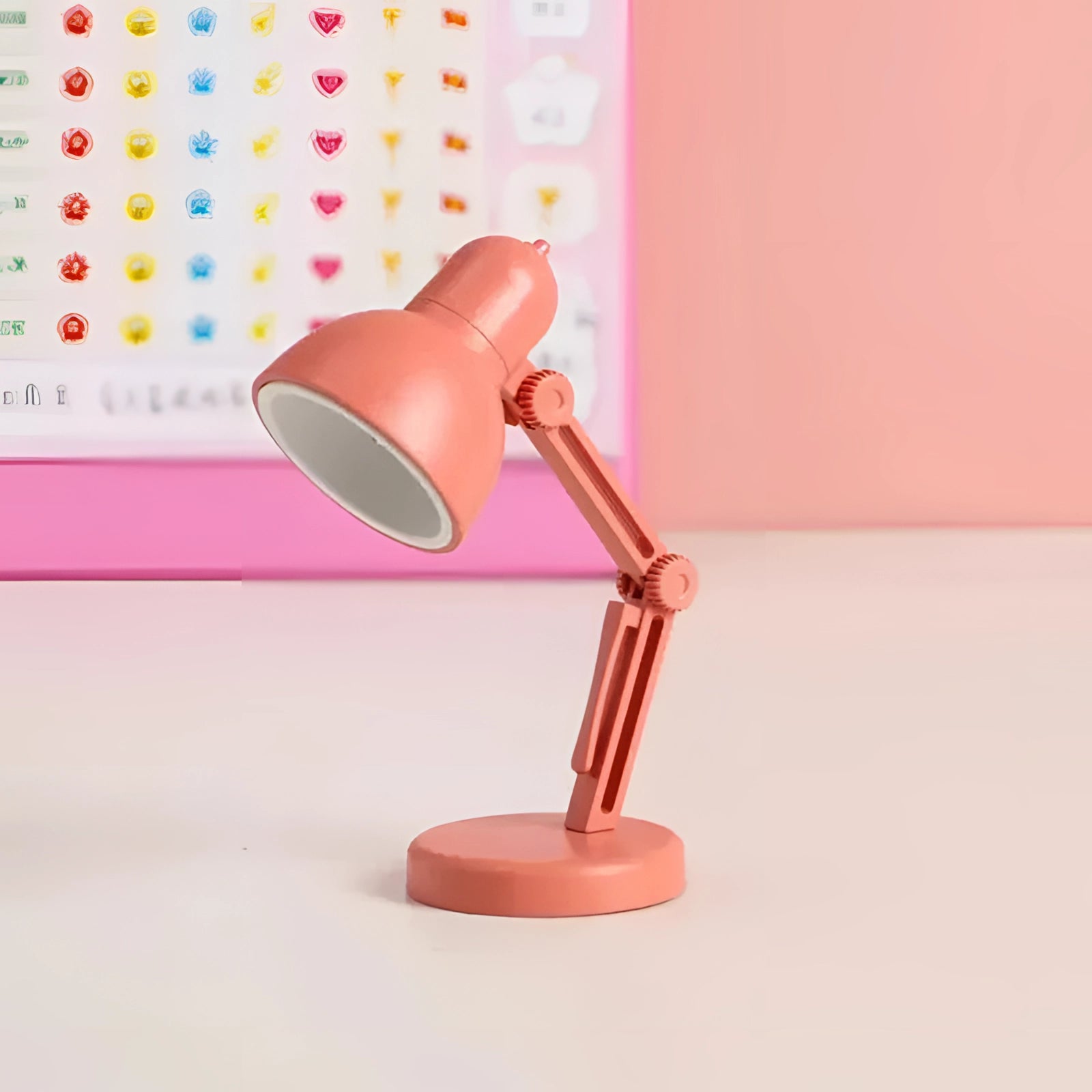 Modern LED desk lamp with a black adjustable arm, featuring a minimalist and compact design, displayed in a coral color.