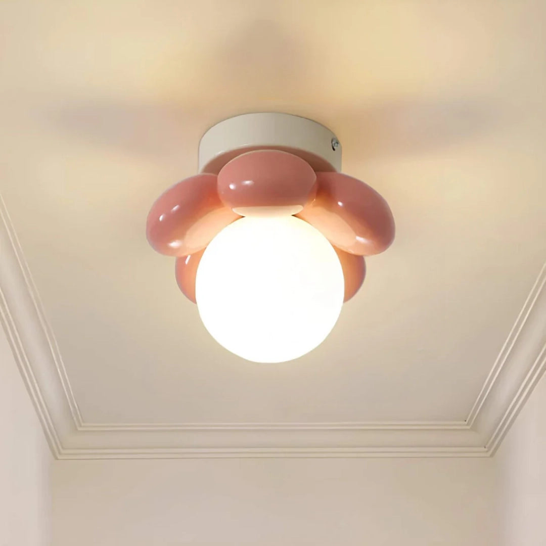 Modern LED ceiling light with a minimalist round design, featuring an opal glass surface and a pink tint, mounted on the ceiling.
